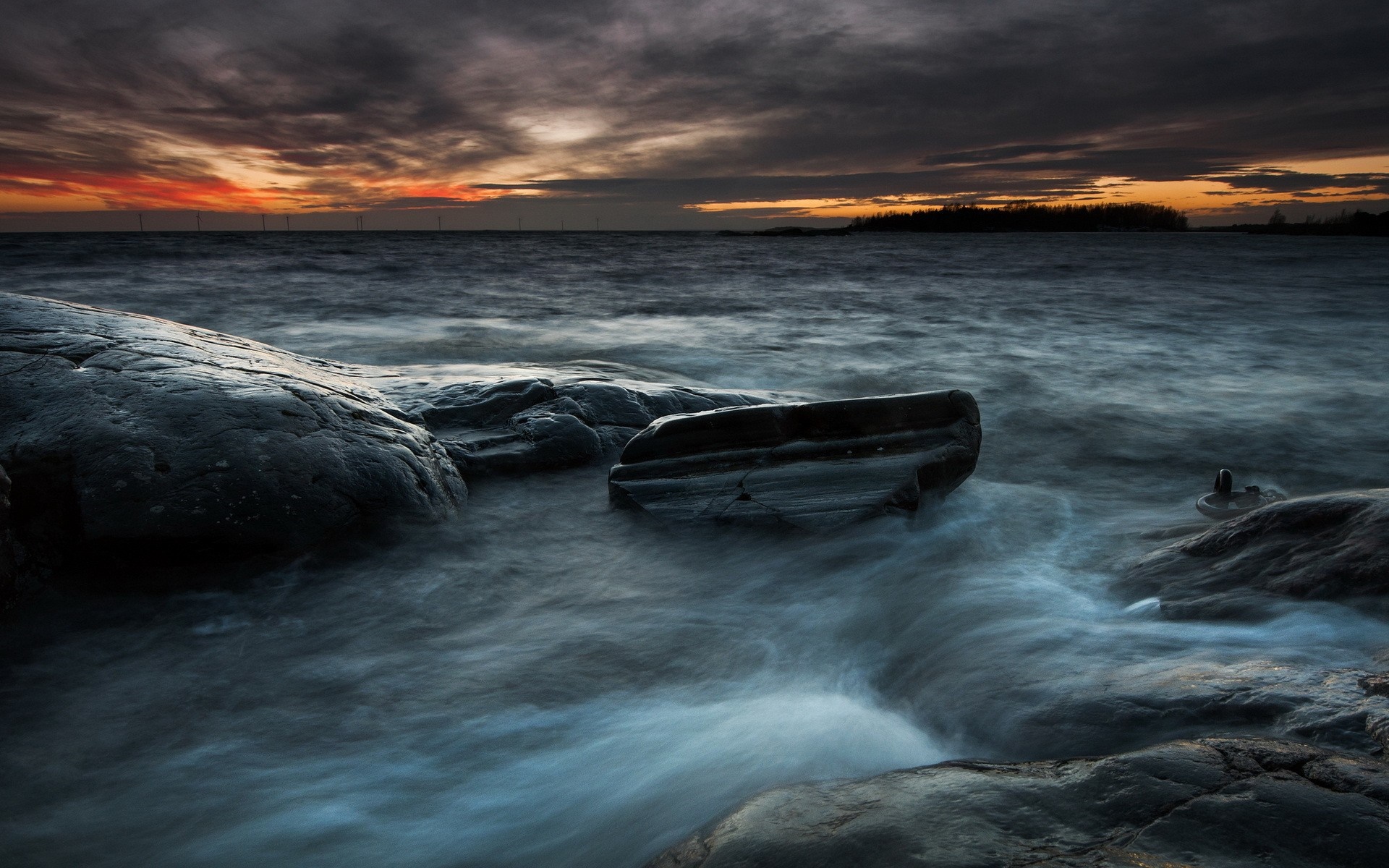 Sunset over the sea with rocks and wind turbines HD Wallpaper