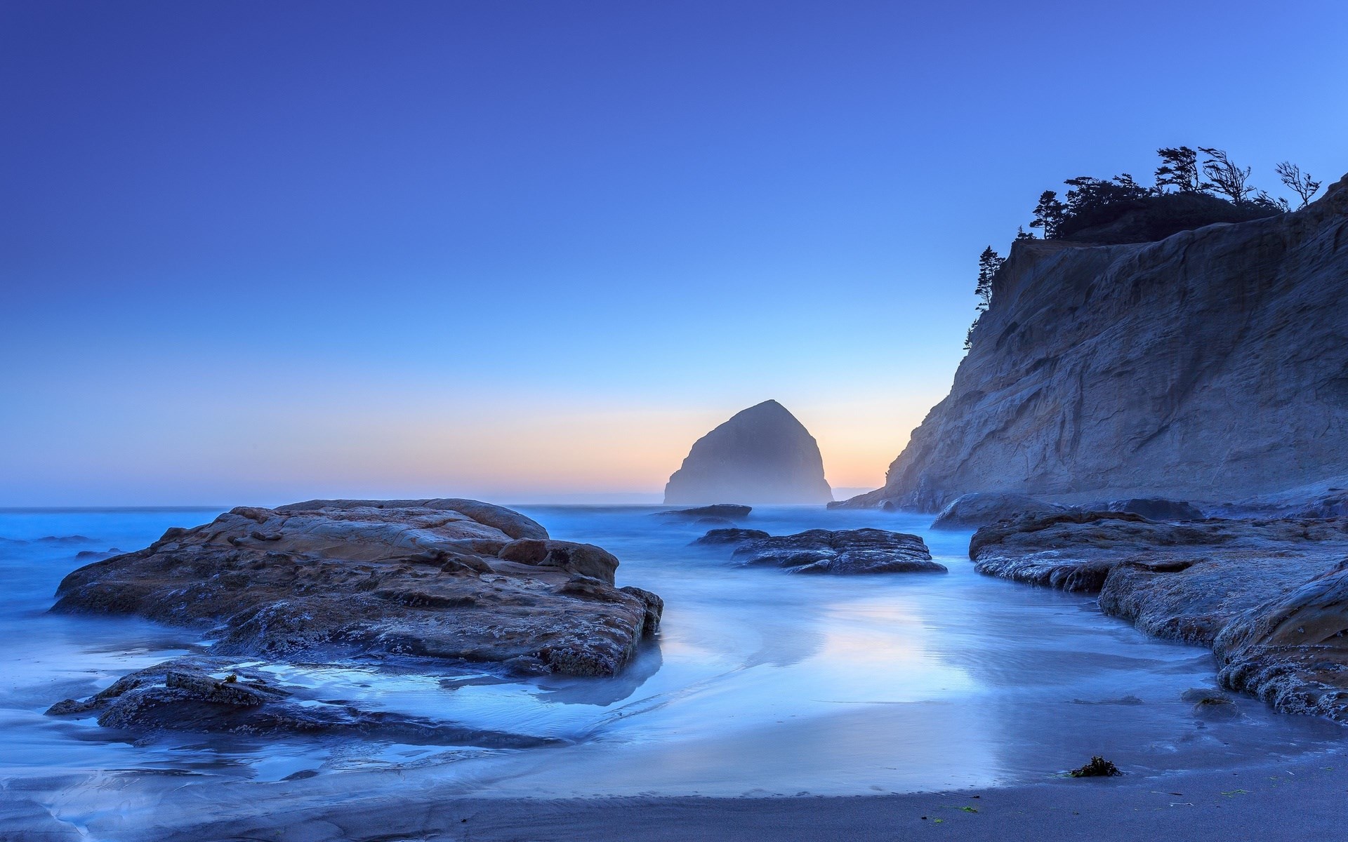 Ocean waves crashing on rocky shore at dusk HD Wallpaper