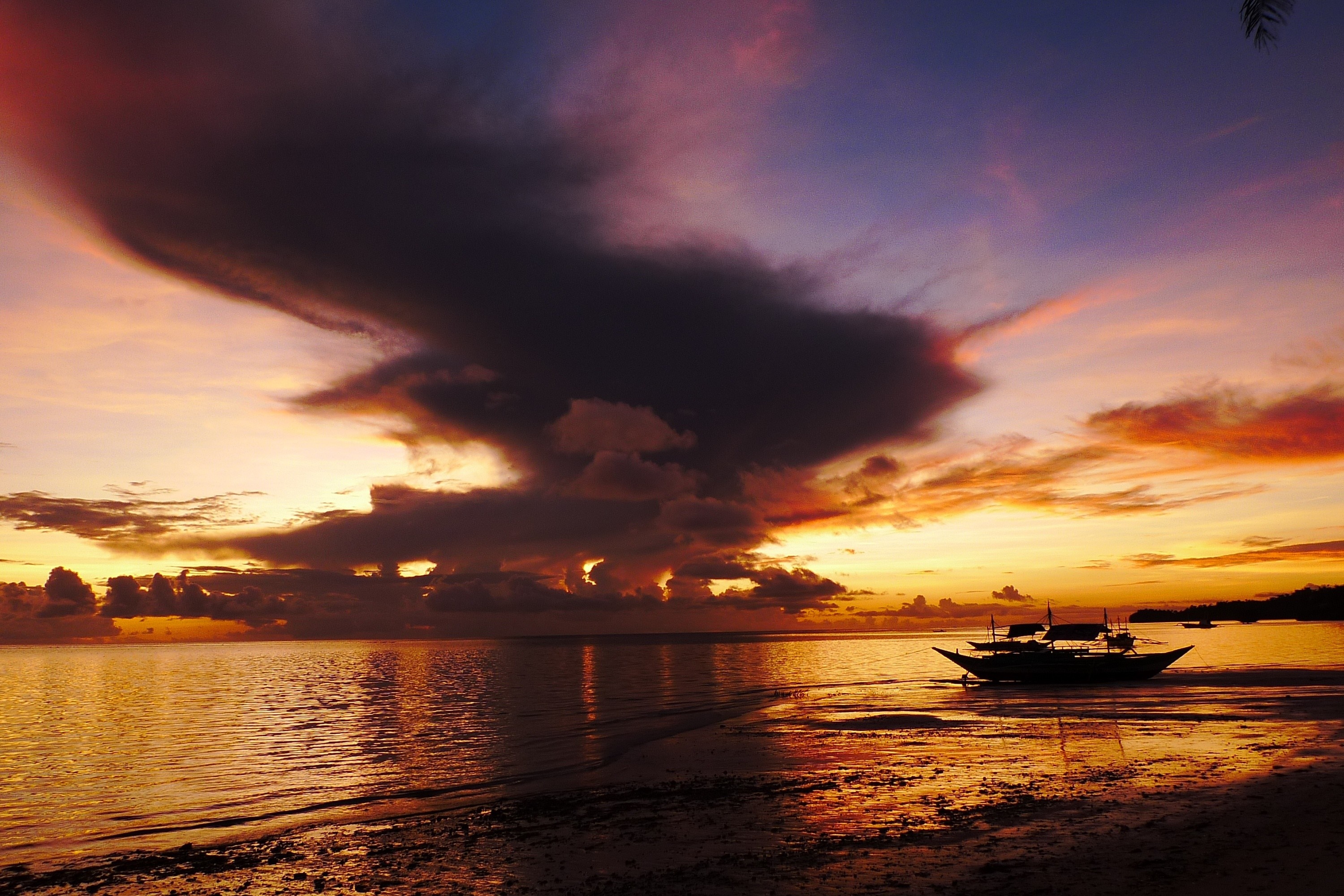 Dramatic sunset over the ocean with a boat on the shore HD Wallpaper