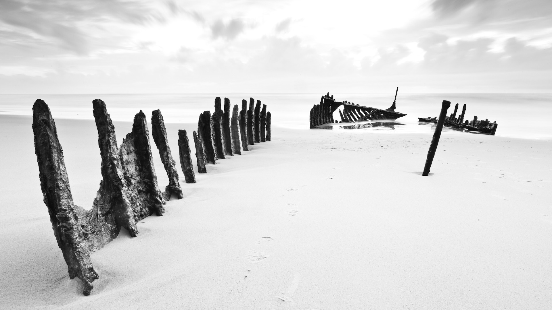 Shipwreck remains on a sandy beach HD Wallpaper
