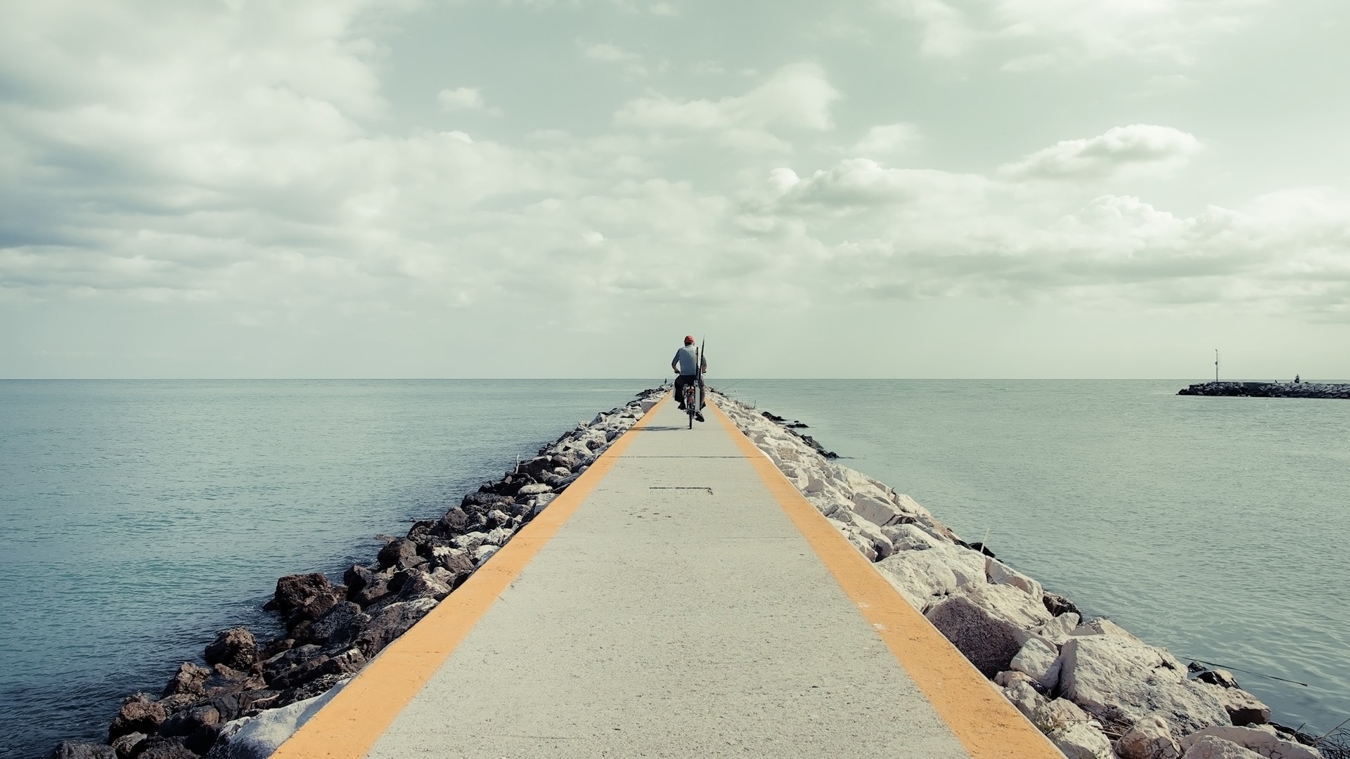 Man riding bicycle on a pier over the sea HD Wallpaper