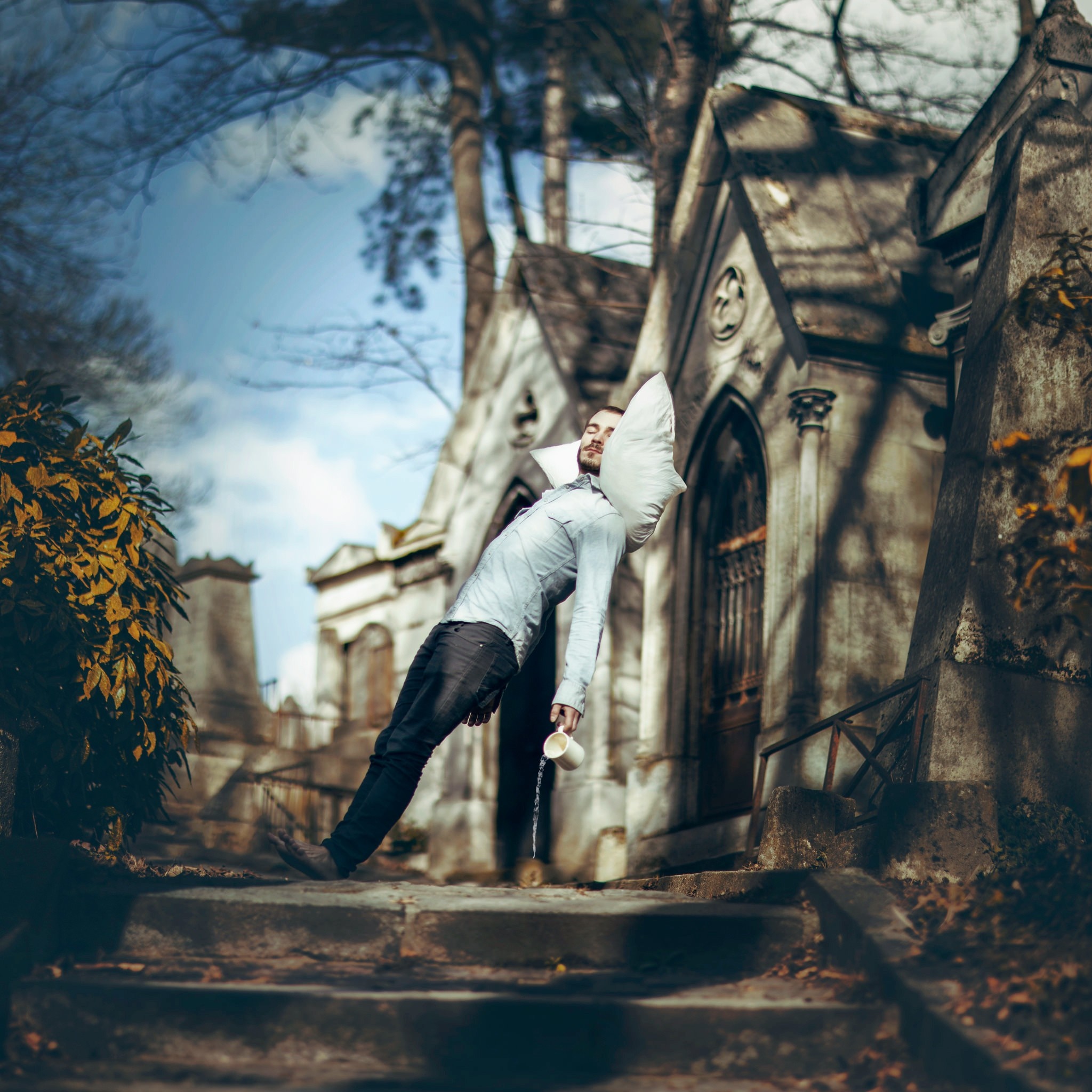 Man sleeping with pillow in cemetery HD Wallpaper