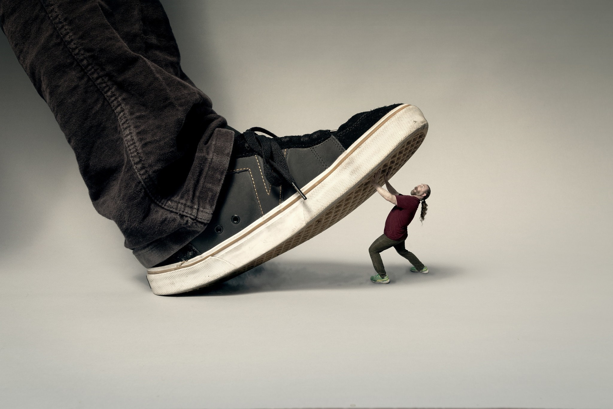 Man struggling to lift a giant sneaker HD Wallpaper