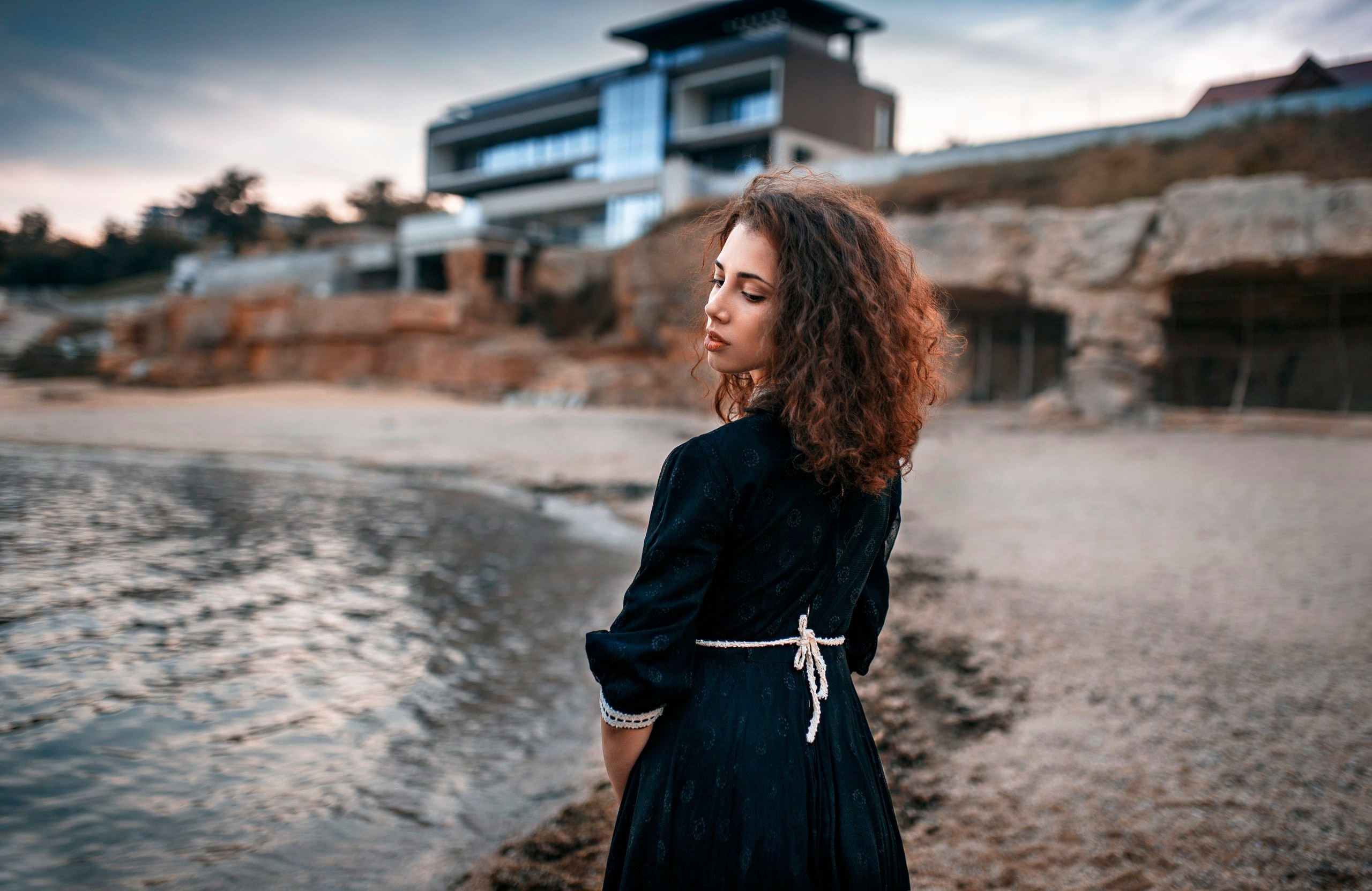 Woman in black dress on beach with modern building HD Wallpaper