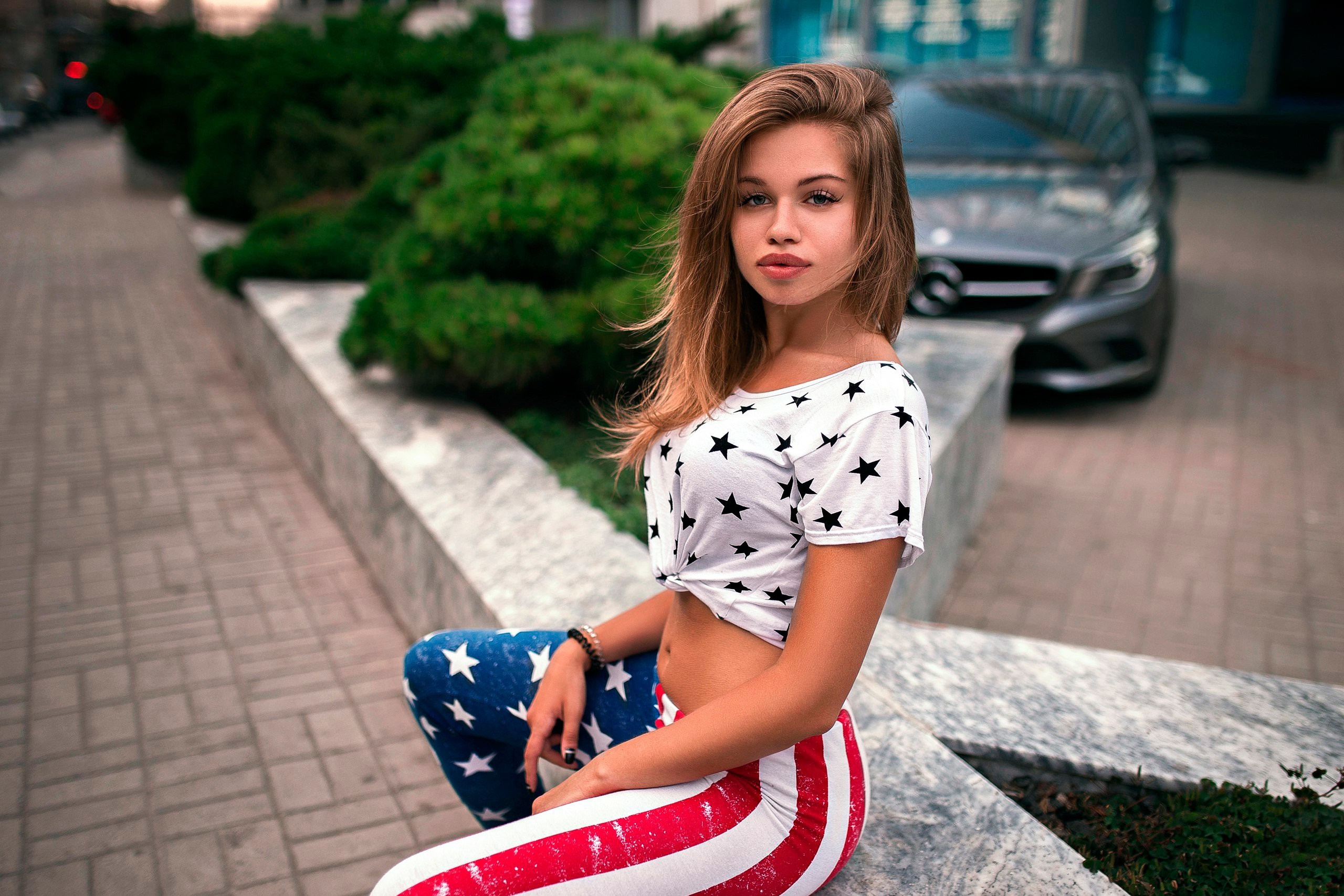 Woman in Stars and Stripes outfit sitting outdoors HD Wallpaper