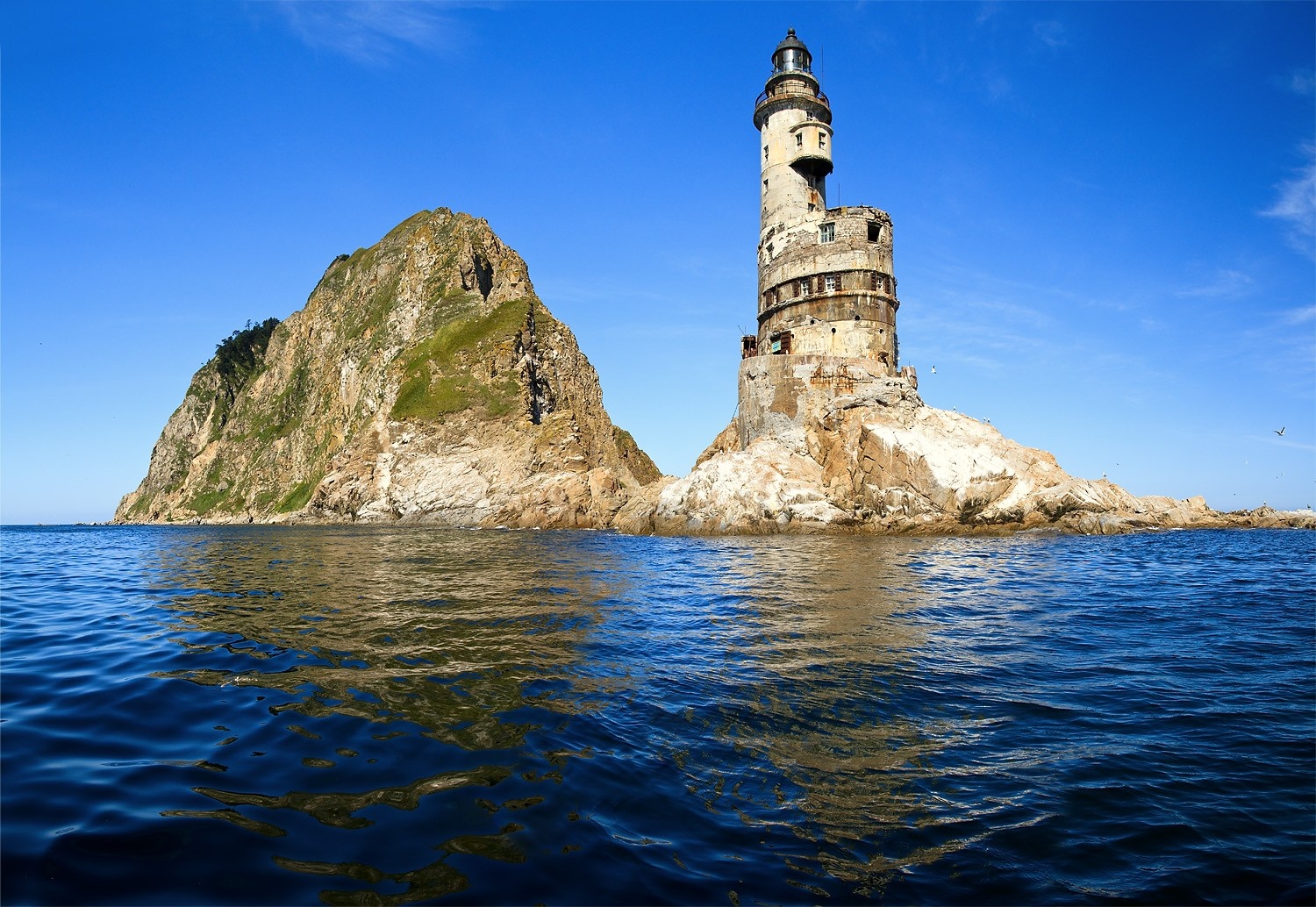 Abandoned lighthouse on a rocky island in the sea HD Wallpaper