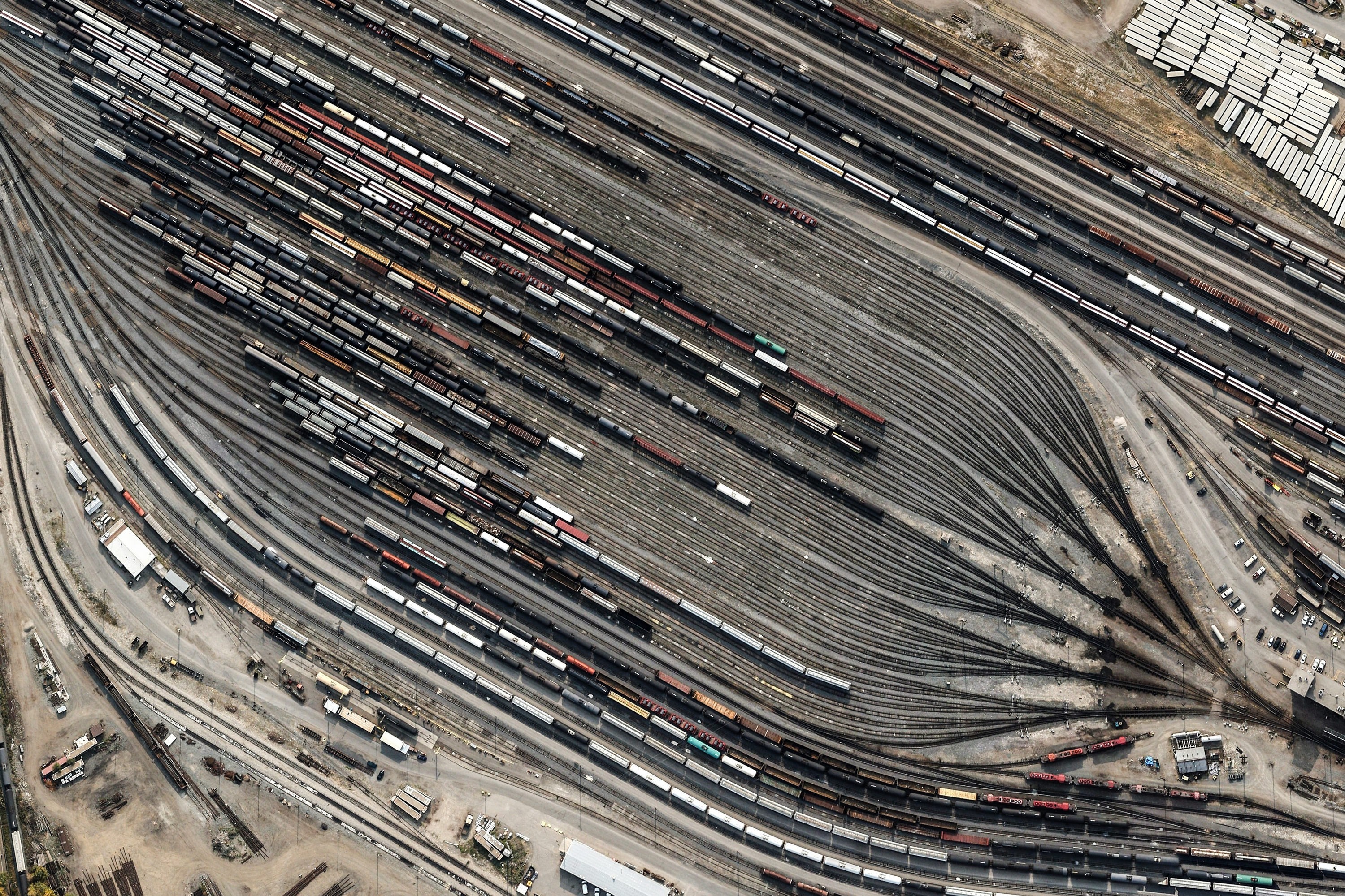 Aerial view of a busy train yard with many tracks and cars HD Wallpaper