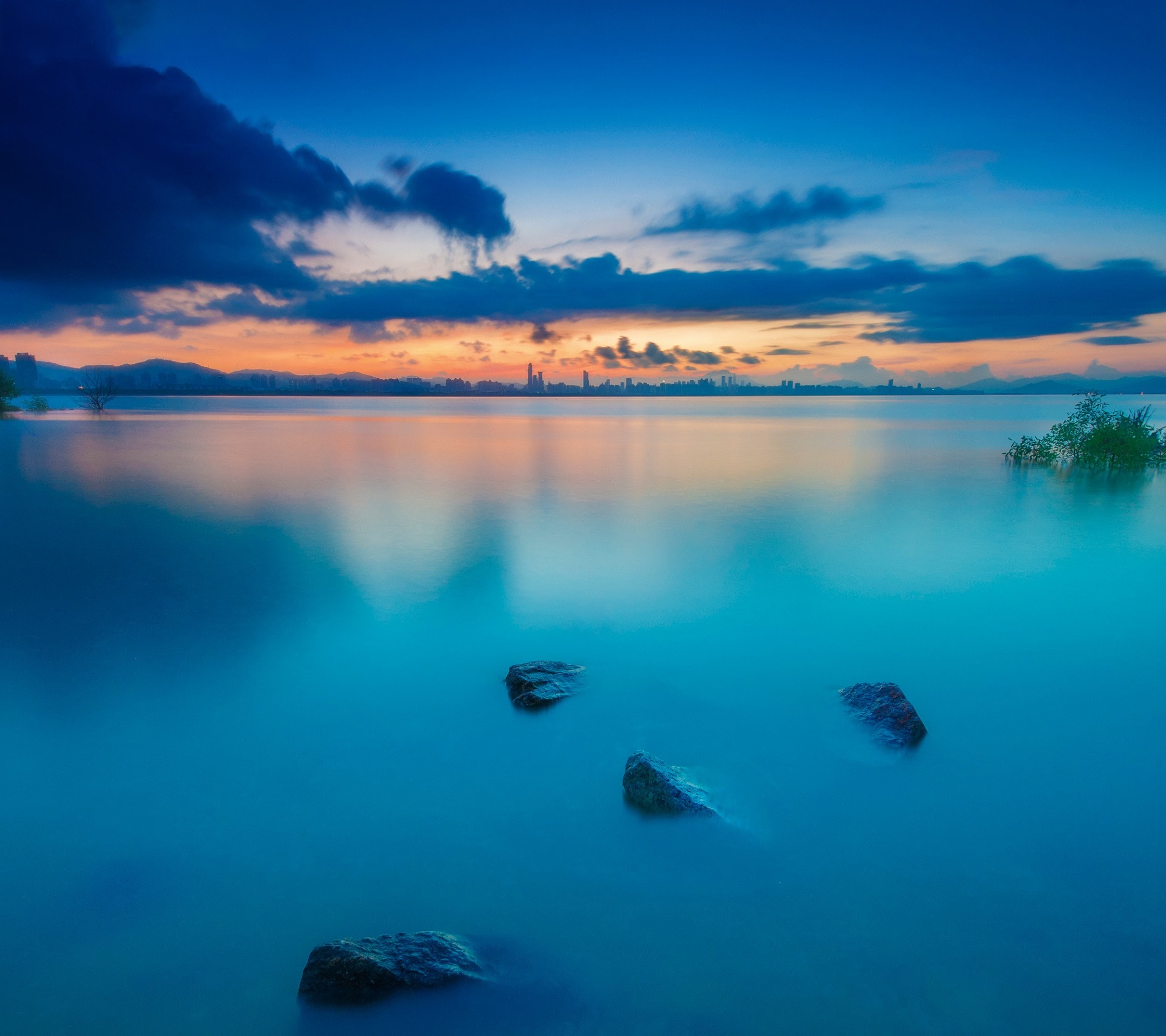 Calm lake at sunset with city skyline reflection HD Wallpaper