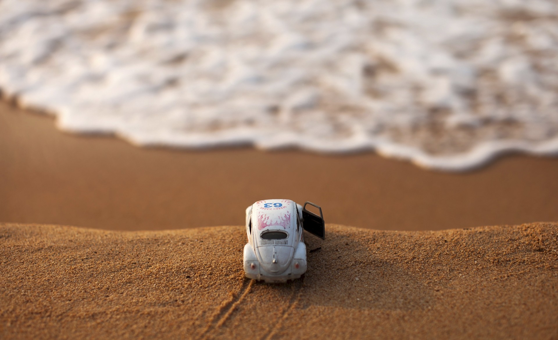 Toy Volkswagen Beetle on a sandy beach with waves HD Wallpaper
