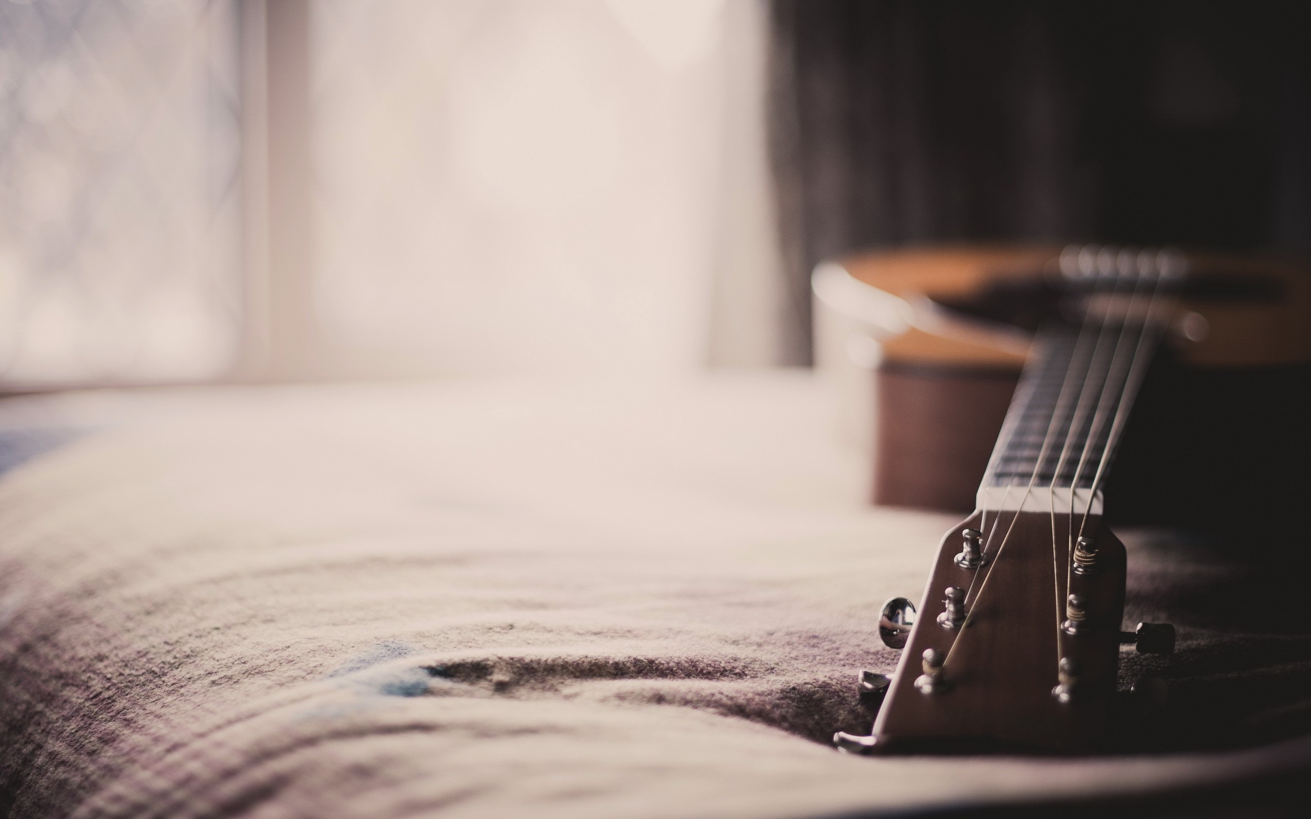 Acoustic guitar headstock on a bed HD Wallpaper