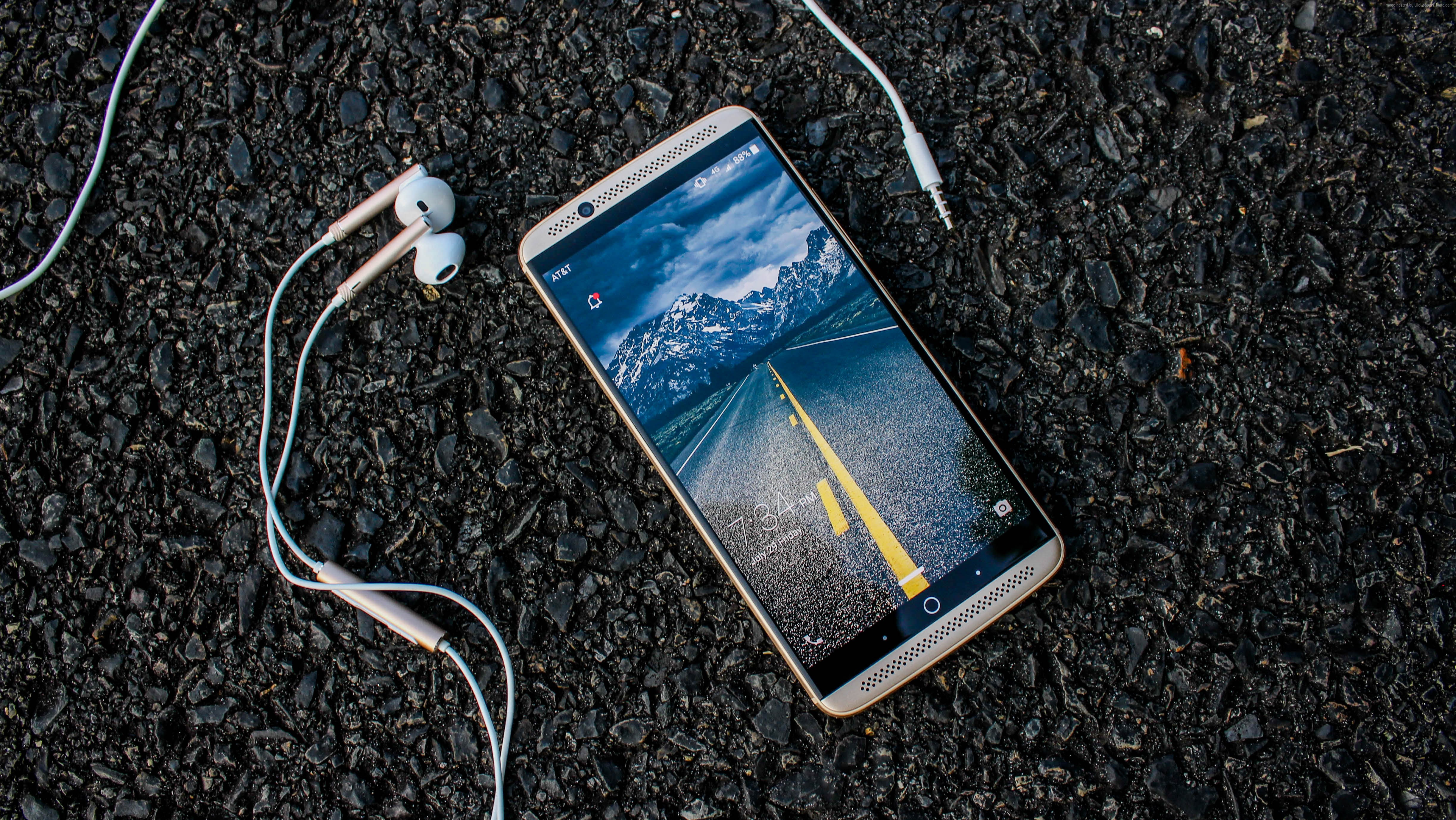 ZTE Gigabit smartphone with earbuds on asphalt HD Wallpaper