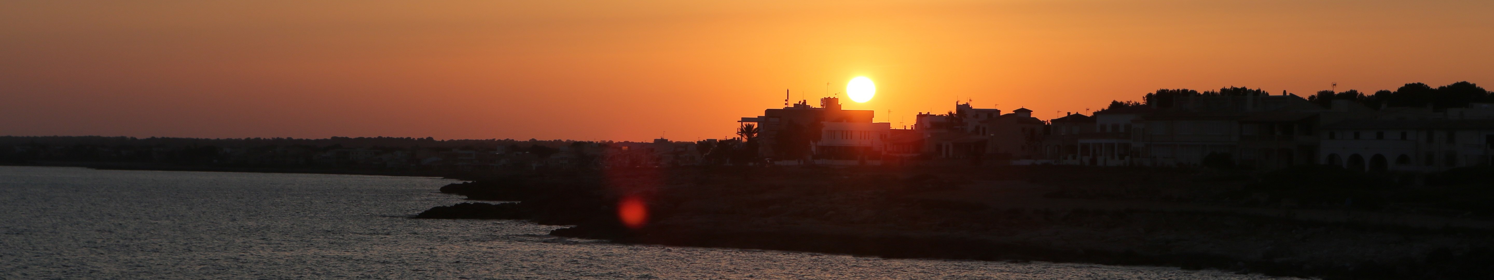 Sunset over a coastal town with the sea HD Wallpaper