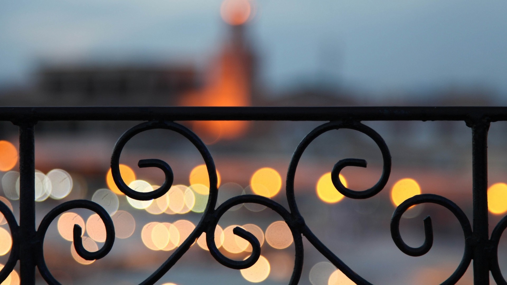 Ornate black railing with bokeh lights in the background HD Wallpaper