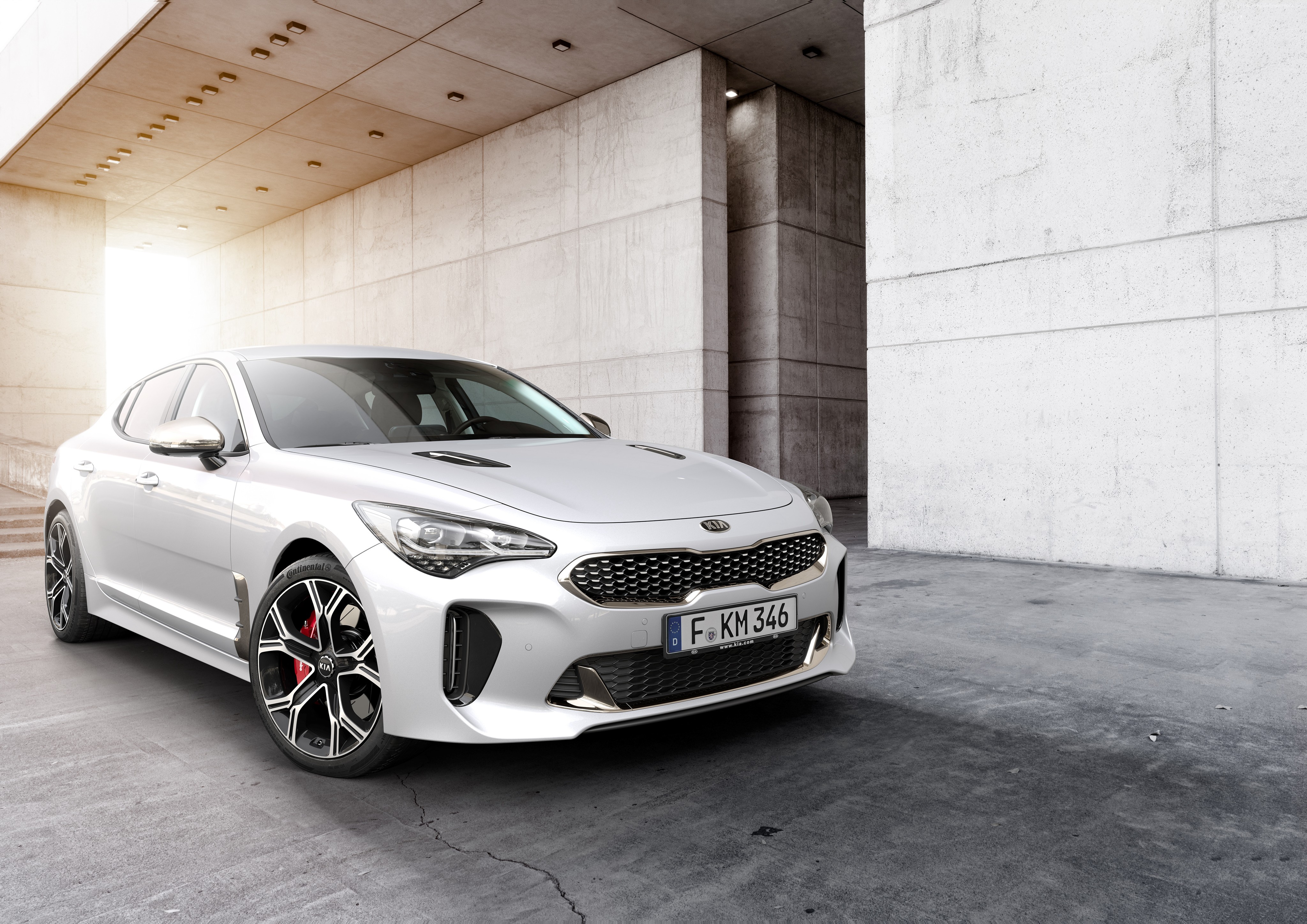 White Kia Stinger GT parked in concrete structure HD Wallpaper