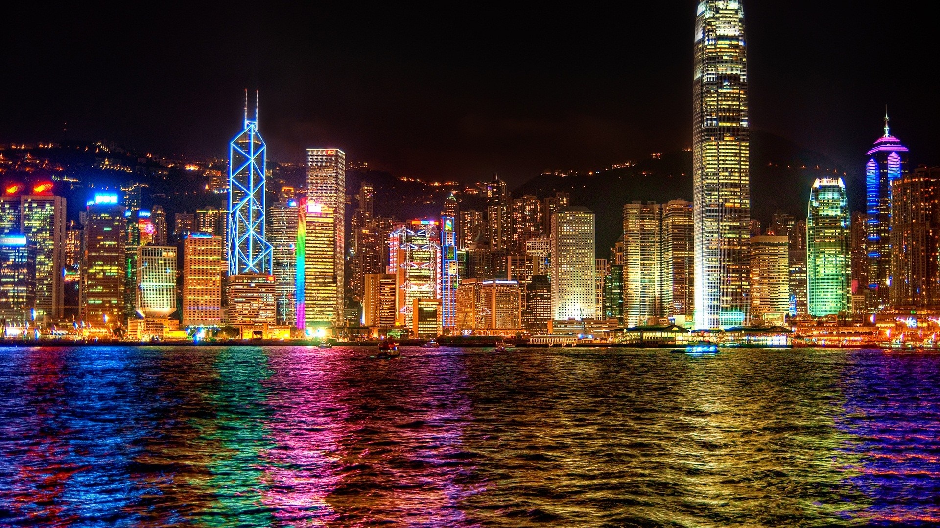Hong Kong skyline at night with colorful lights reflecting on water HD Wallpaper