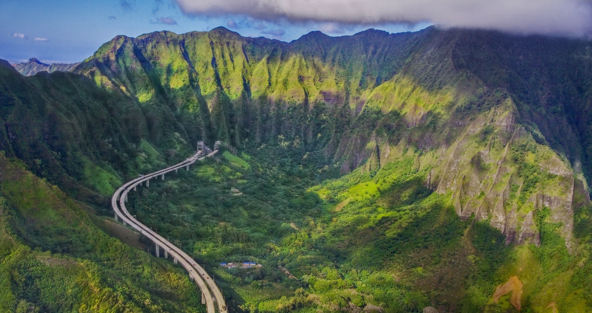 Aerial view of a highway through a lush green valley in Oahu, Hawaii HD Wallpaper