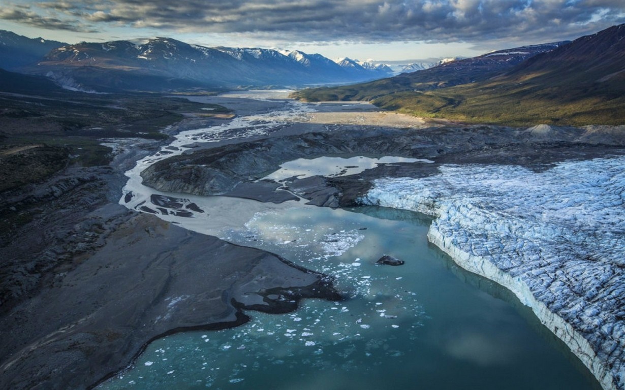 Aerial view of a glacial valley with a river and mountains HD Wallpaper