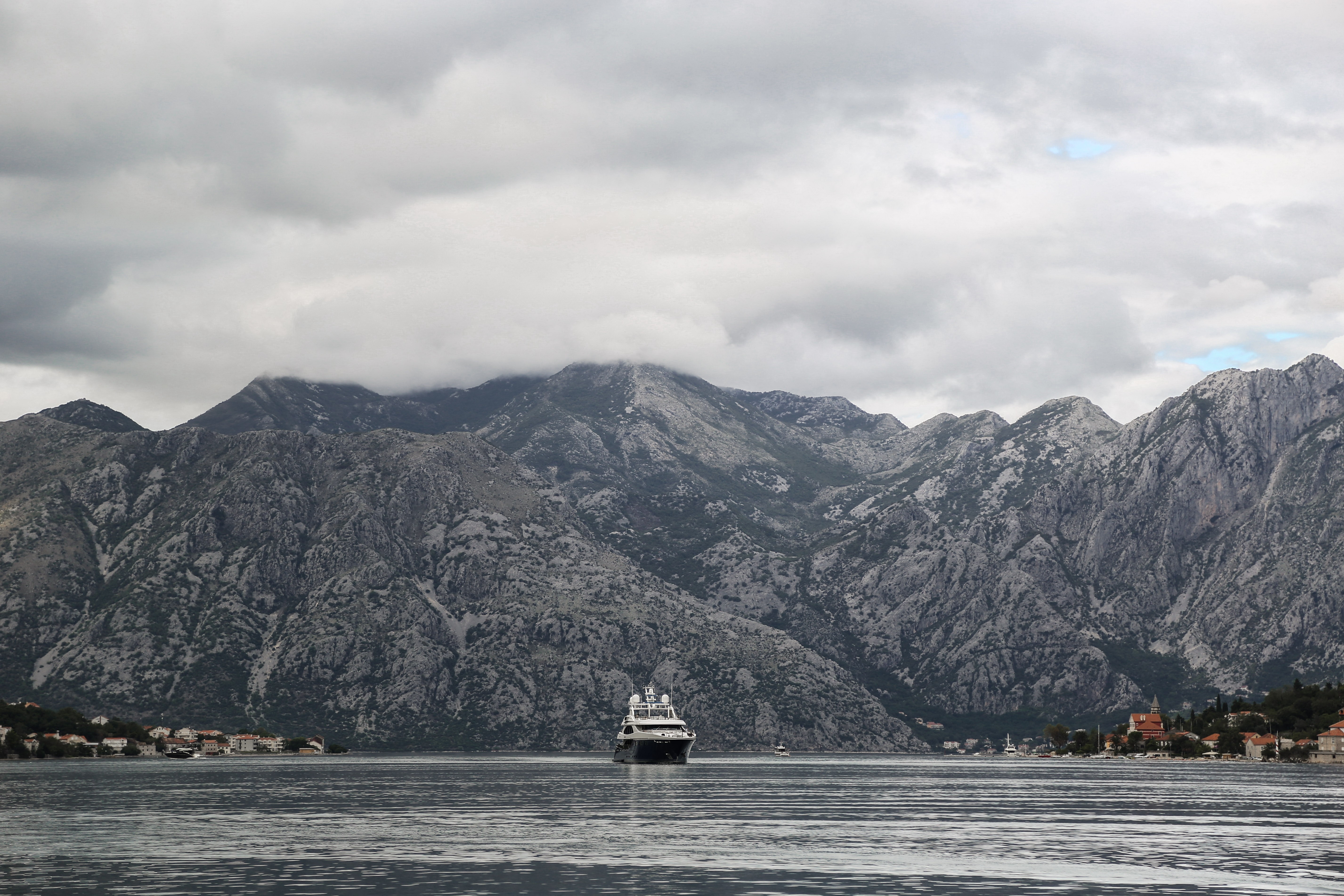 Yacht in a bay with mountains and a coastal town HD Wallpaper