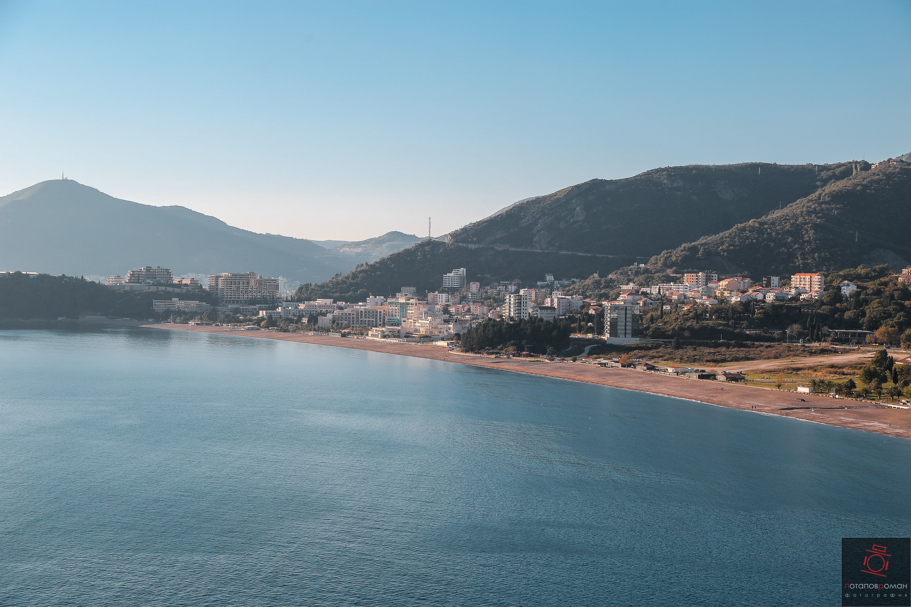 Coastal city nestled between mountains and sea HD Wallpaper