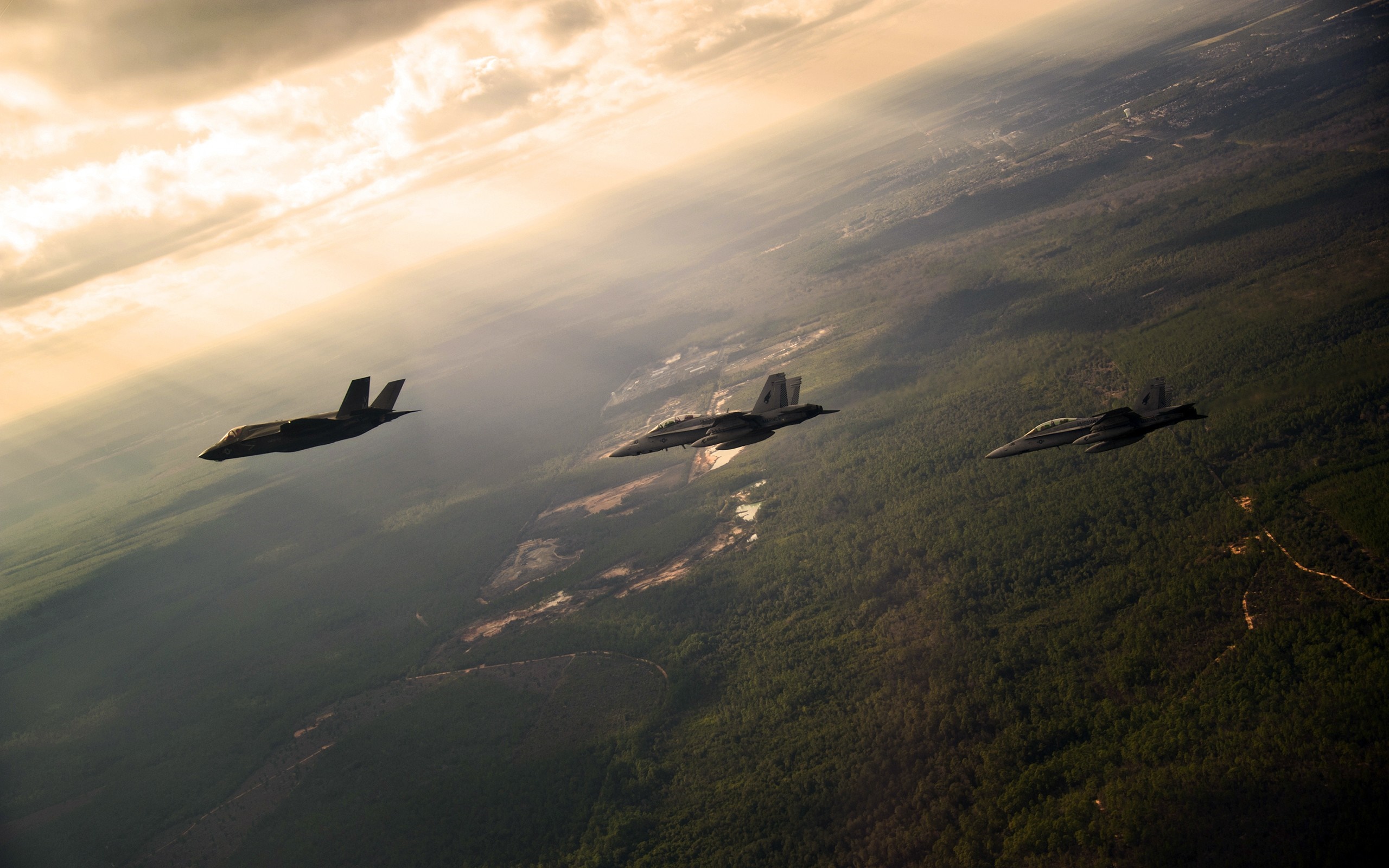 Three military jets flying over a forest at sunrise HD Wallpaper