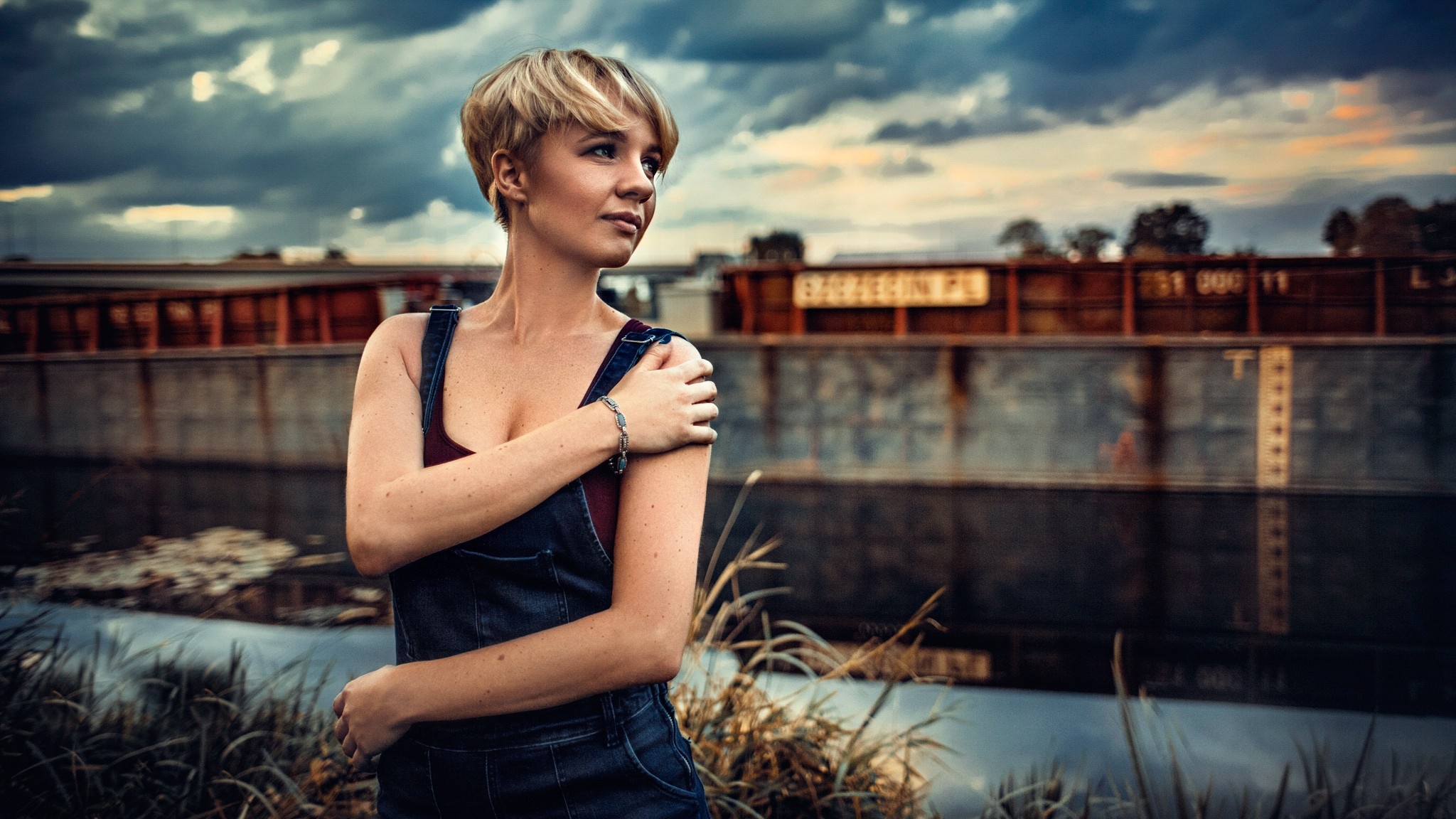 Woman in denim overalls posing by a barge HD Wallpaper