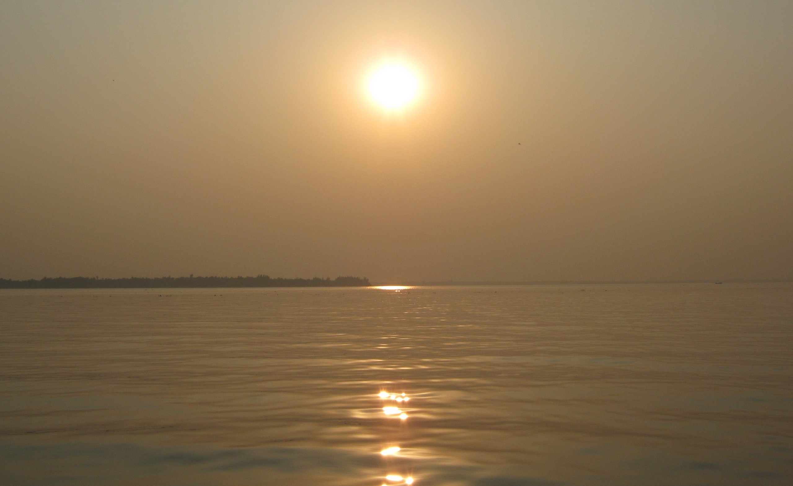 Sunset over a calm body of water with a distant shoreline HD Wallpaper