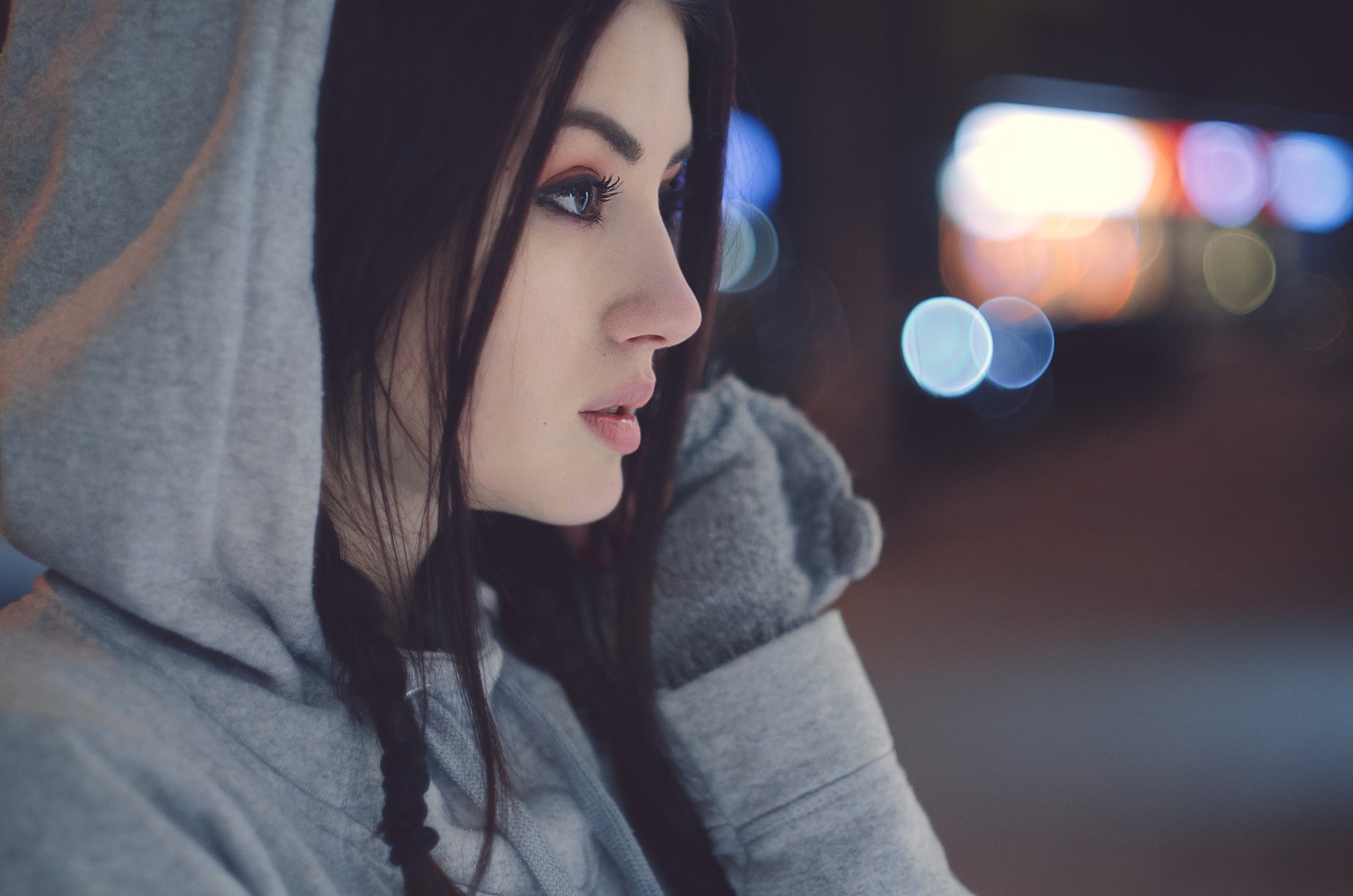 Woman in a grey hoodie looking away at night HD Wallpaper