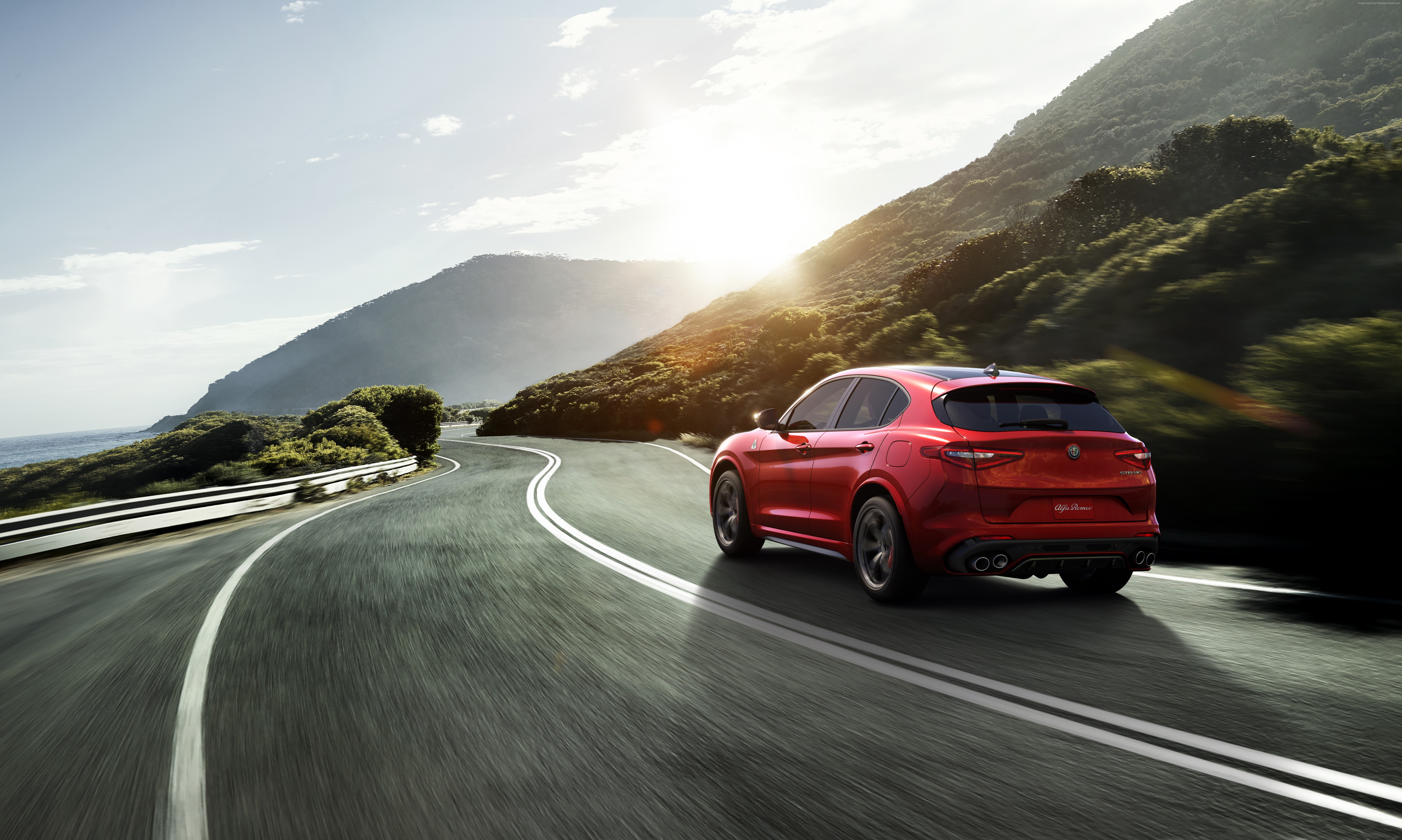 Red Alfa Romeo Stelvio Quadrifoglio driving on coastal road HD Wallpaper