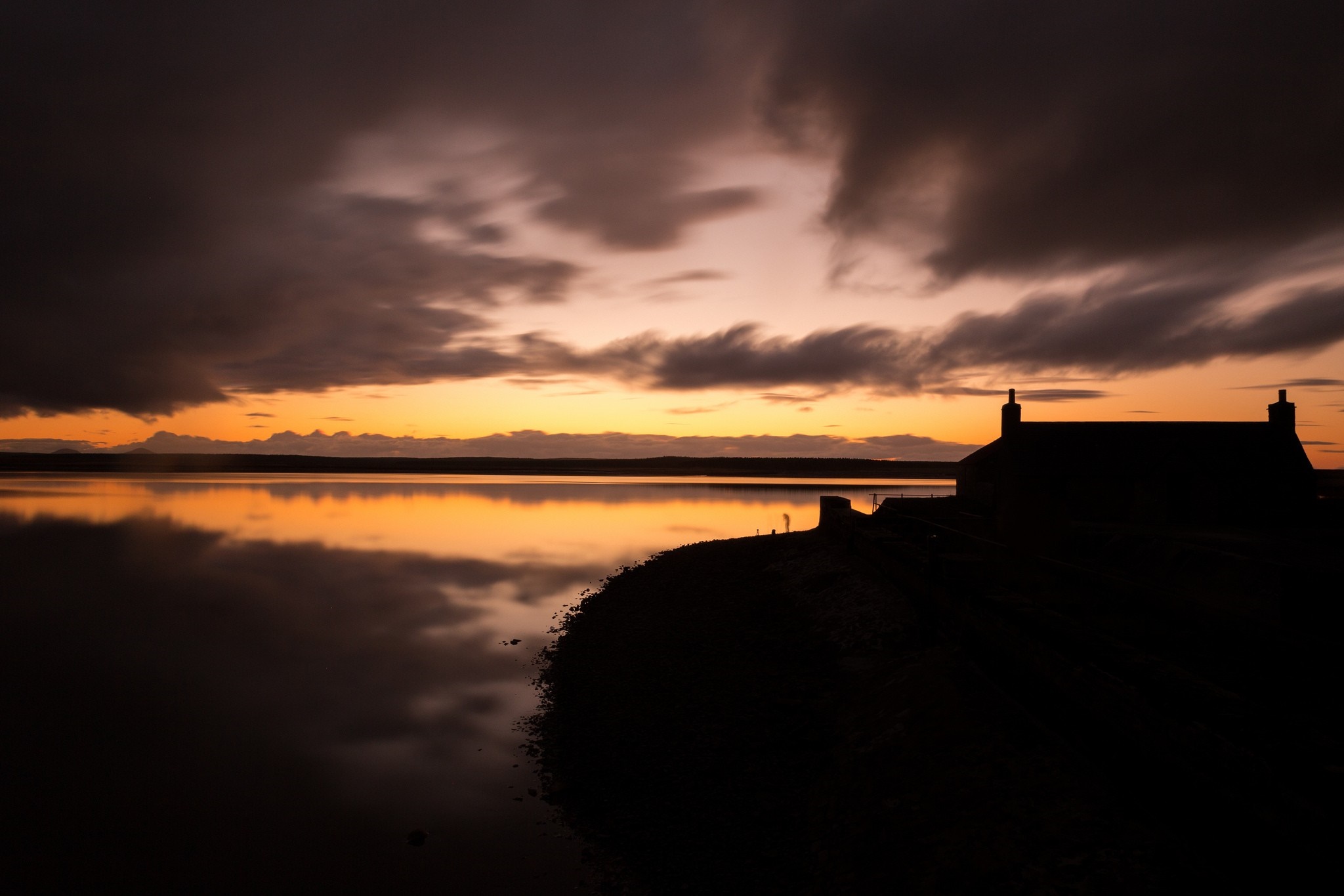 Silhouette of a house by the water at sunset HD Wallpaper
