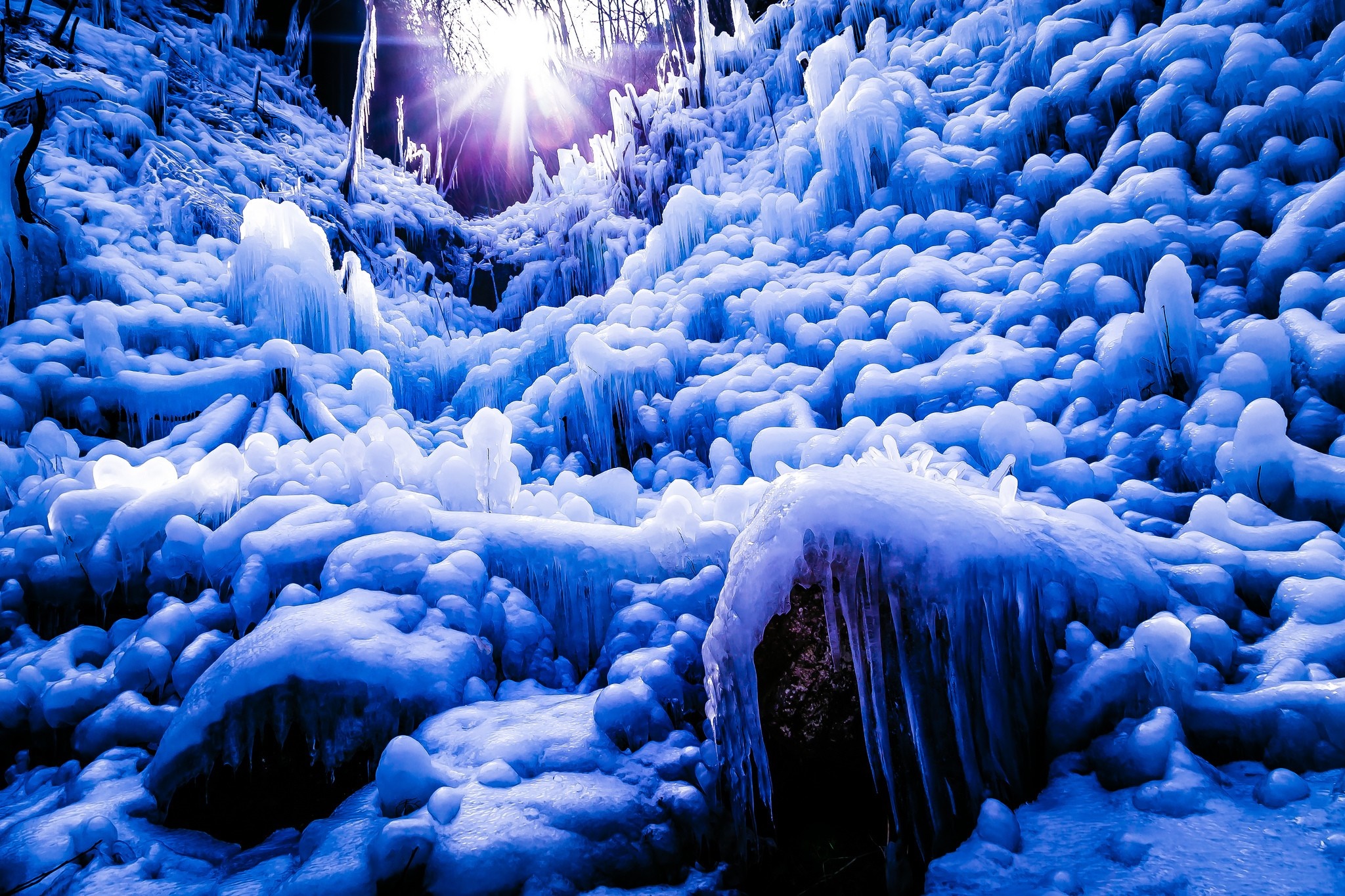 Frozen waterfall with icicles and sunbeams HD Wallpaper