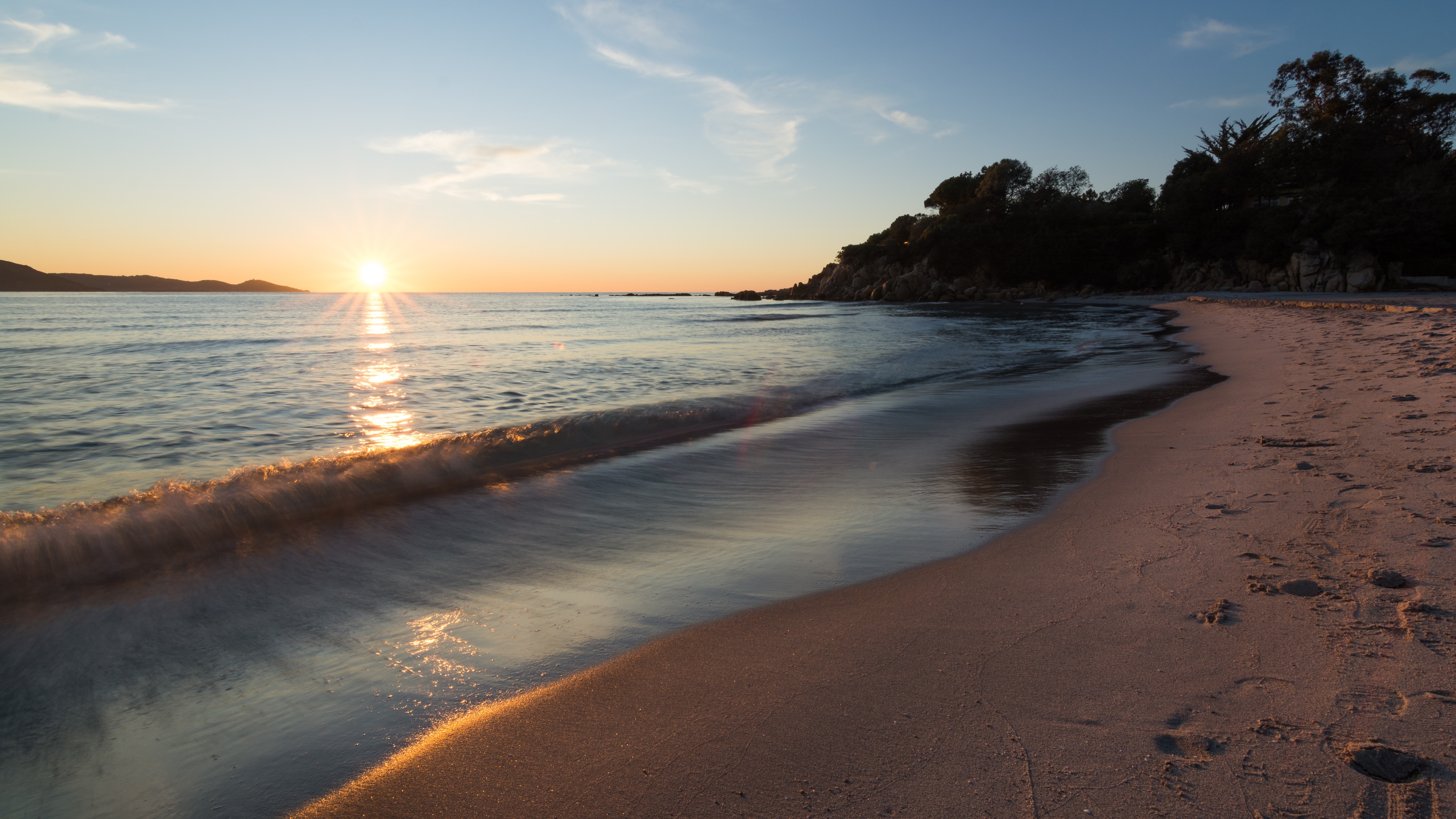 Sunset over a calm sea with waves on a sandy beach HD Wallpaper