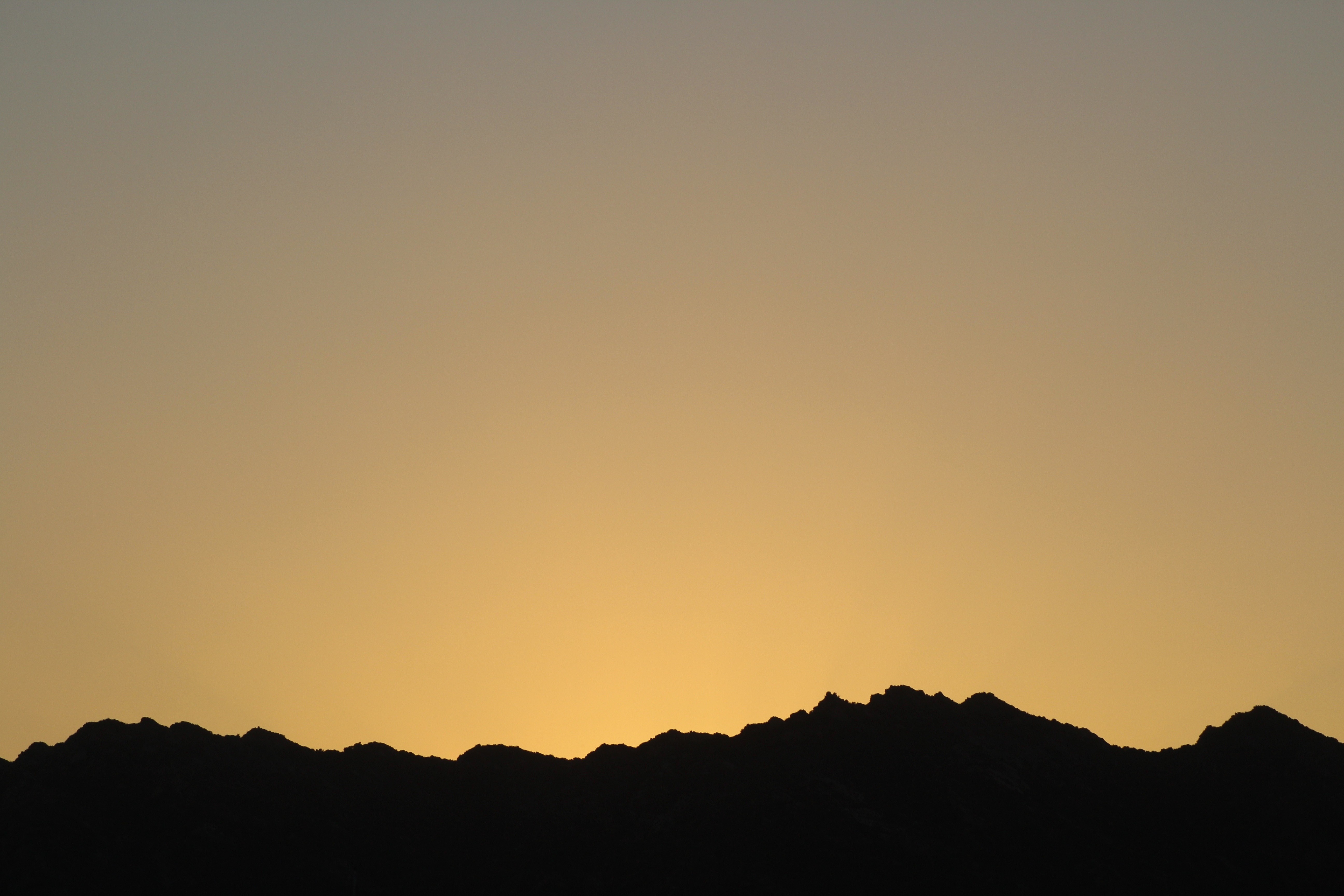 Silhouette of mountains against a sunset sky HD Wallpaper