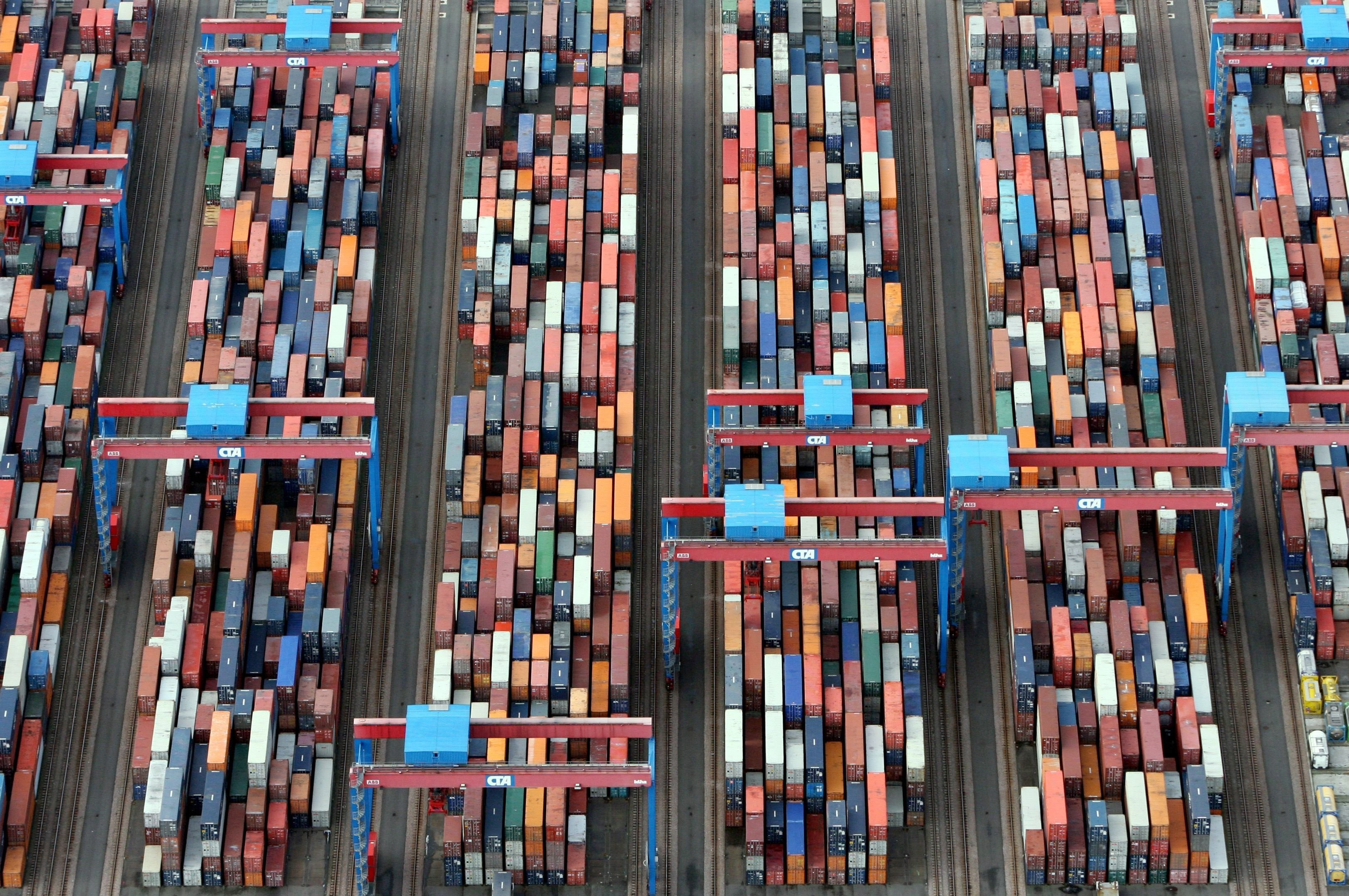 Aerial view of a busy shipping port with many containers and cranes HD Wallpaper