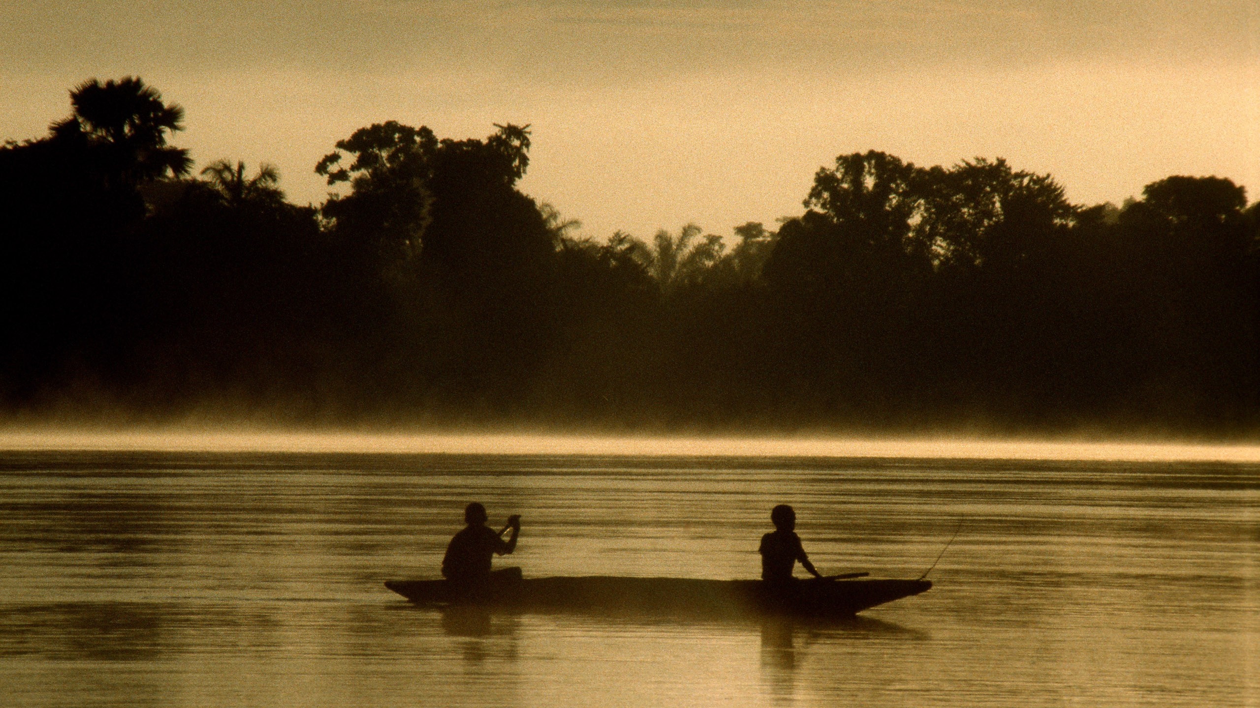 Two people in a canoe on a misty river at sunrise HD Wallpaper