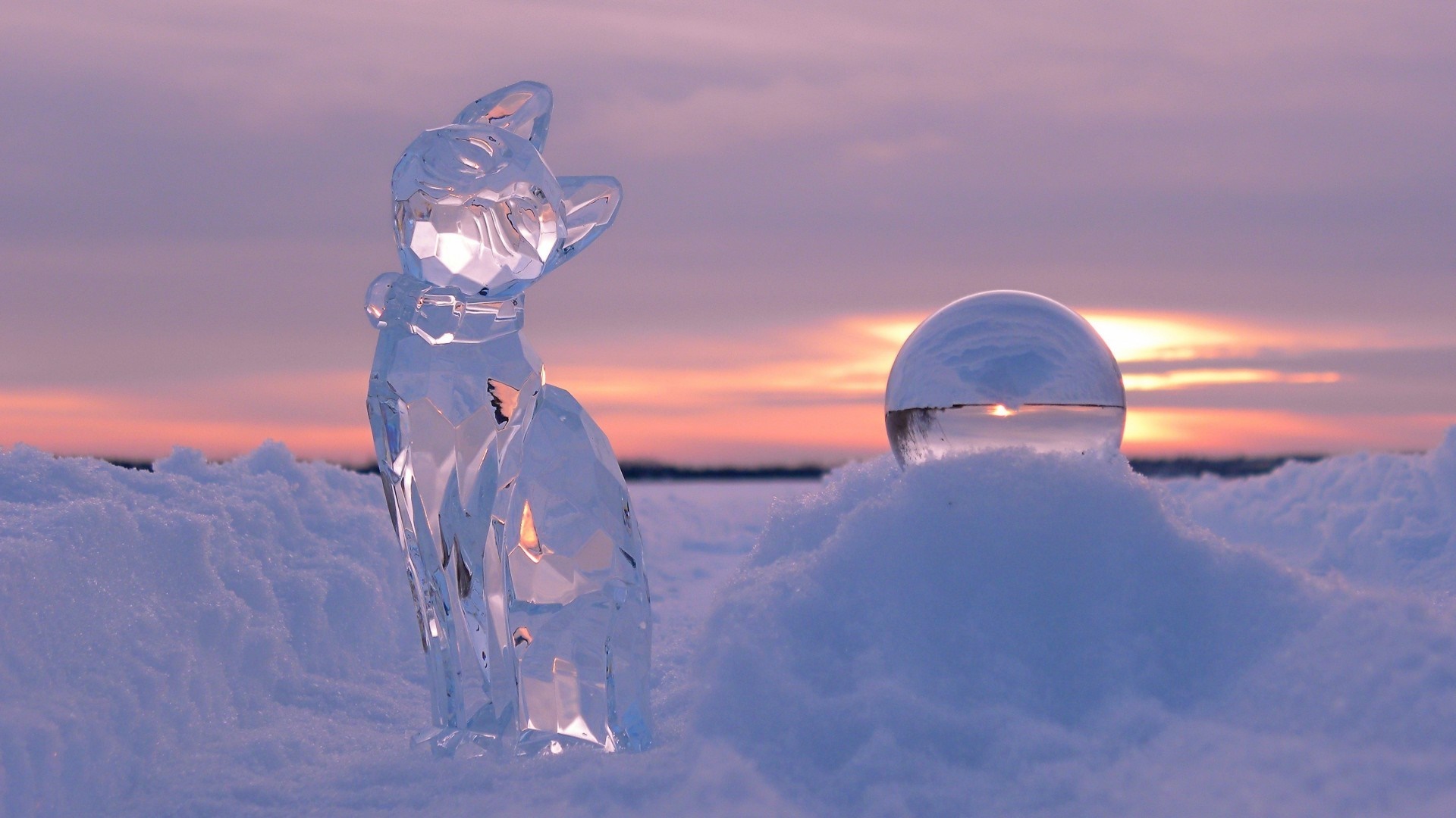 Ice cat sculpture and glass sphere in snow at sunset HD Wallpaper