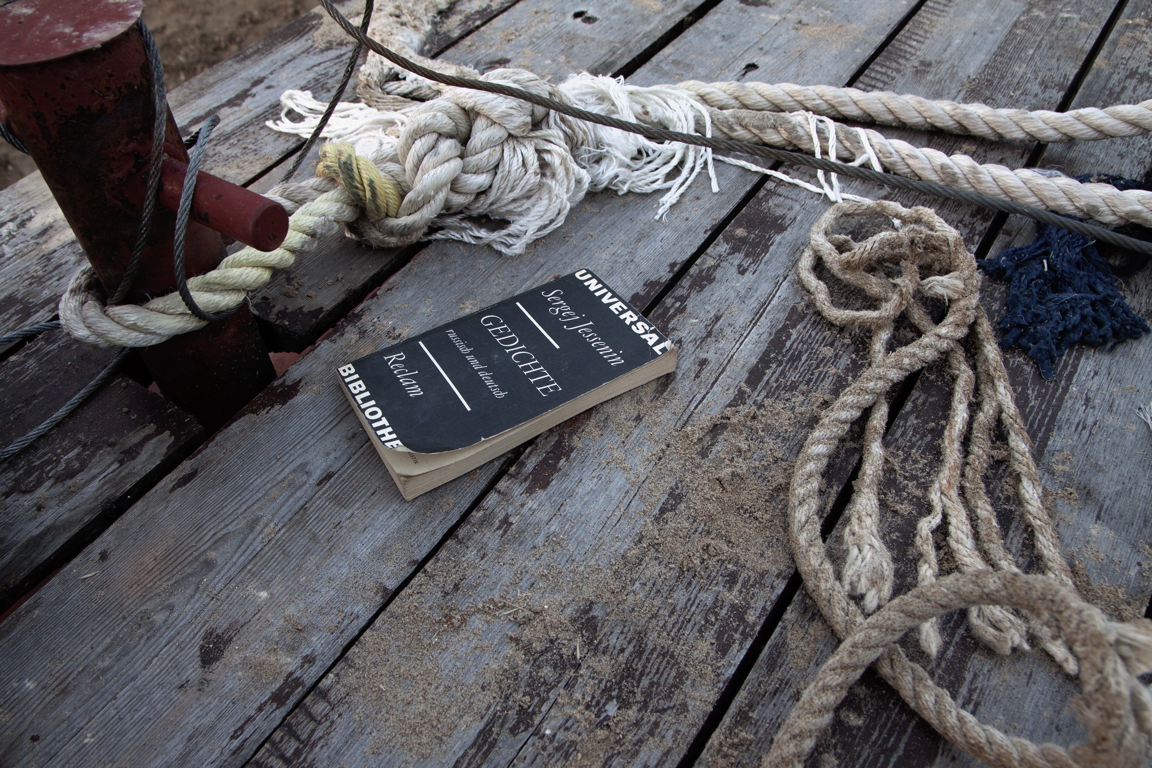 Book of poems on a wooden pier with ropes HD Wallpaper