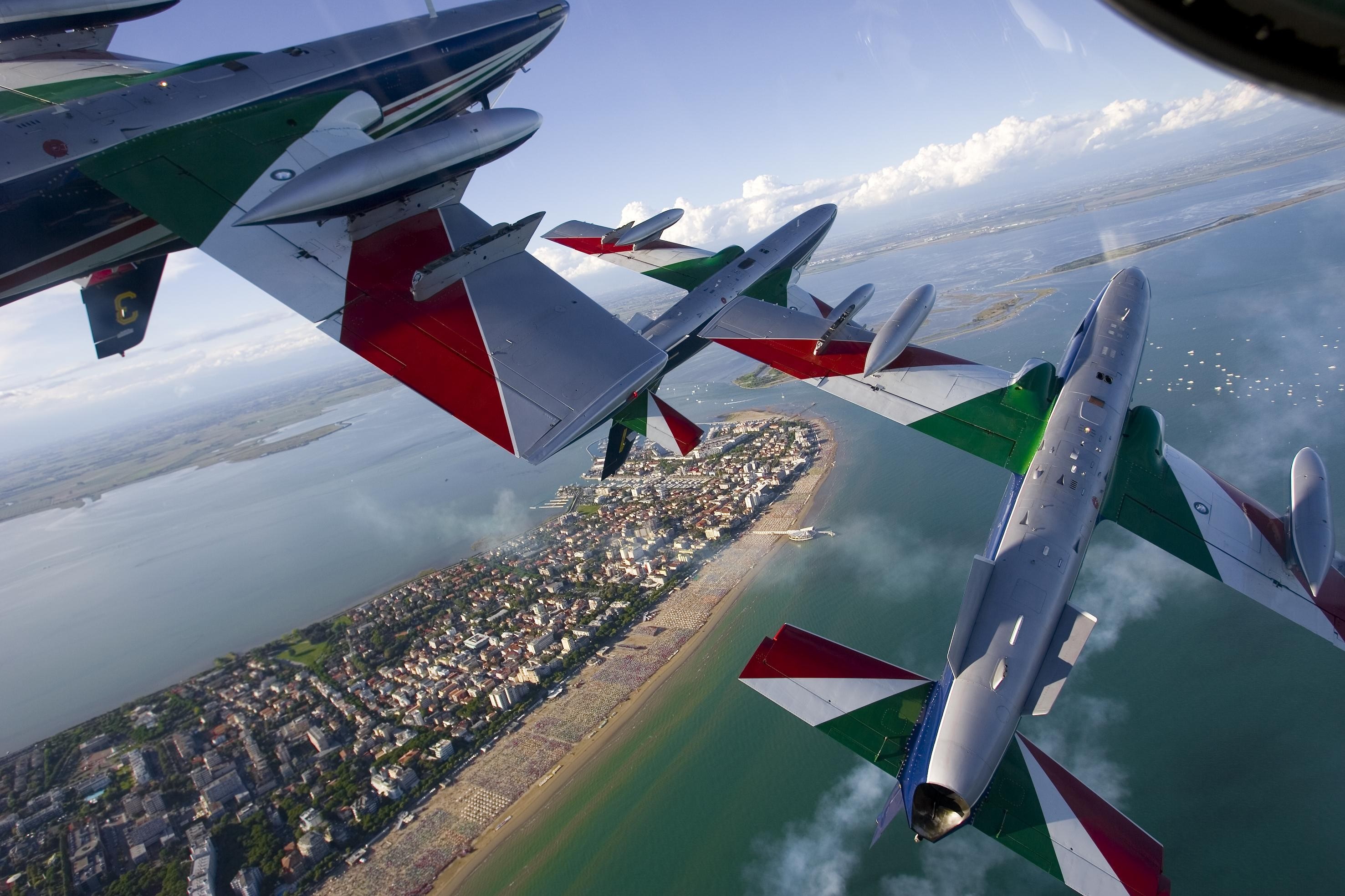 Frecce Tricolori aerobatic team flying over a coastal town HD Wallpaper