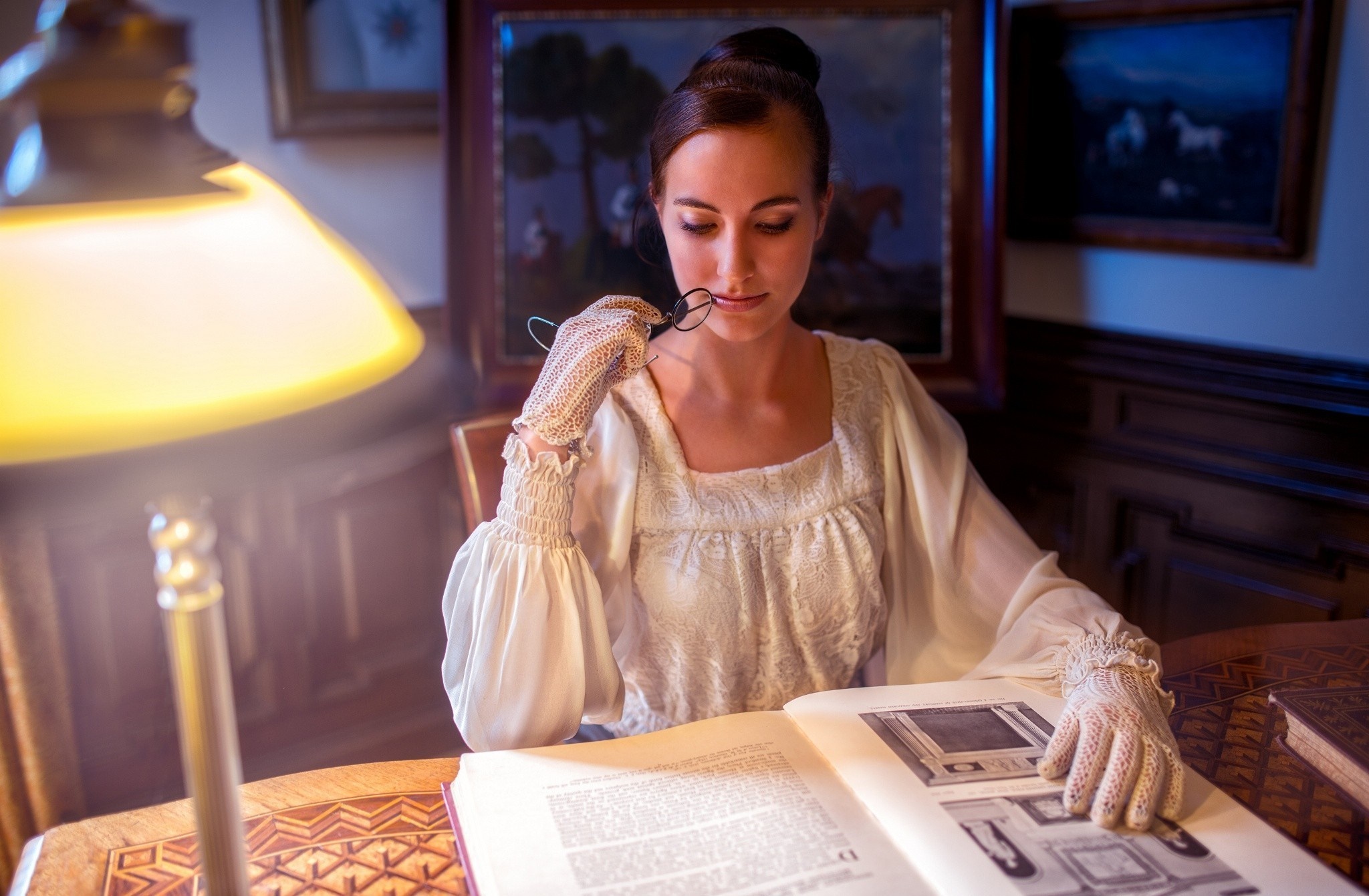 Woman in vintage dress reading a book by lamplight HD Wallpaper