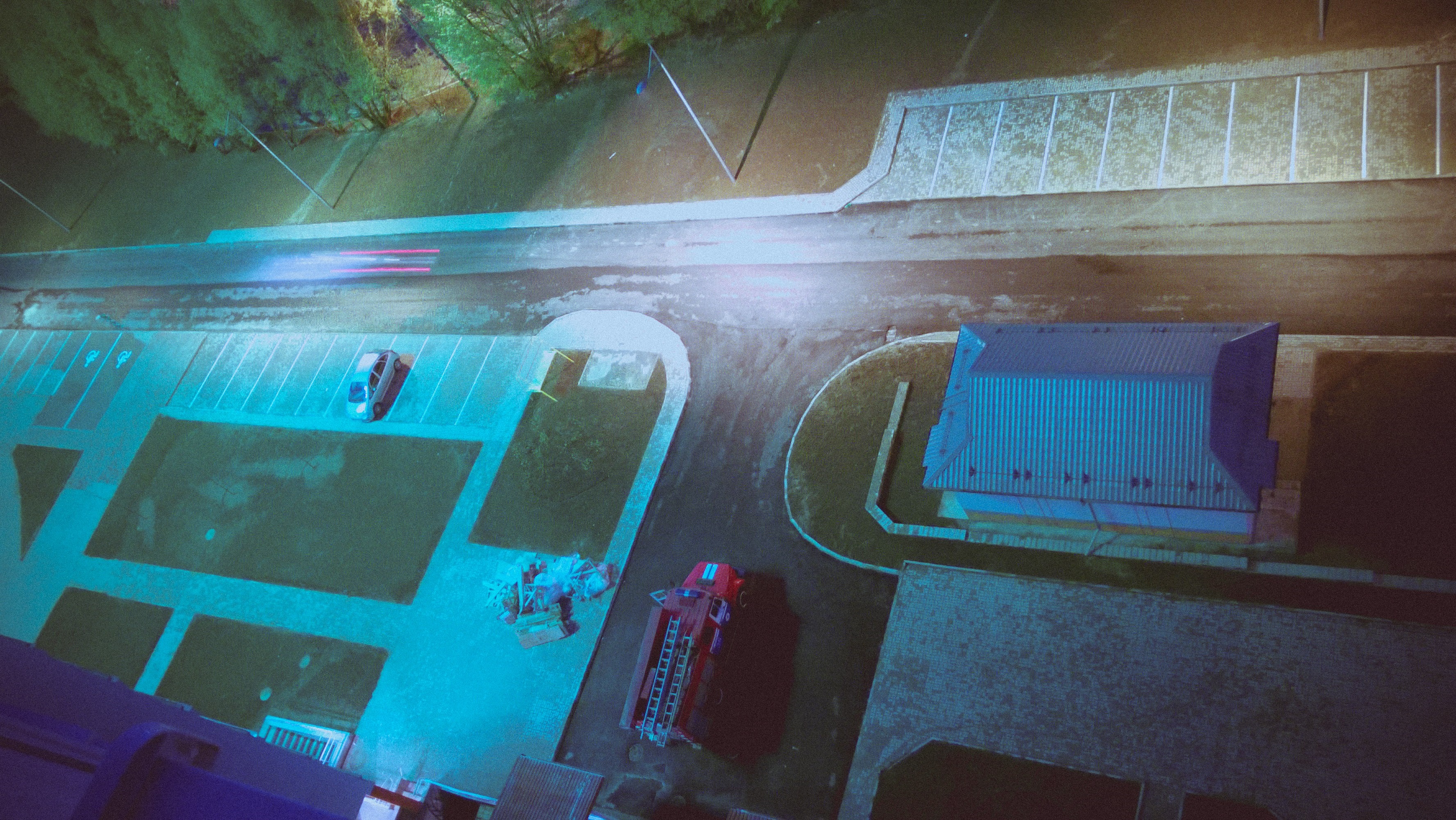 Aerial view of a parking lot with a fire truck and cars at night HD Wallpaper