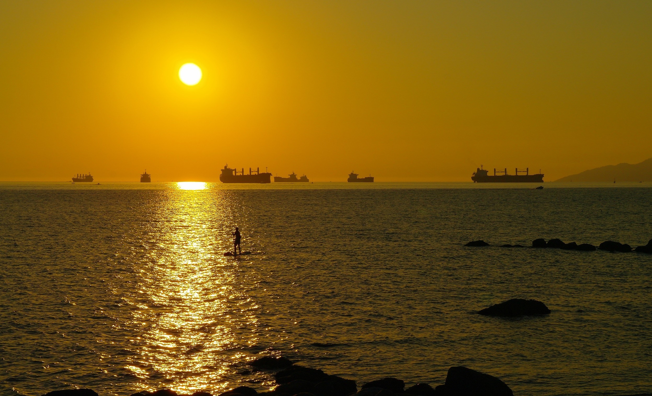 Sunset over the ocean with ships and a paddleboarder HD Wallpaper