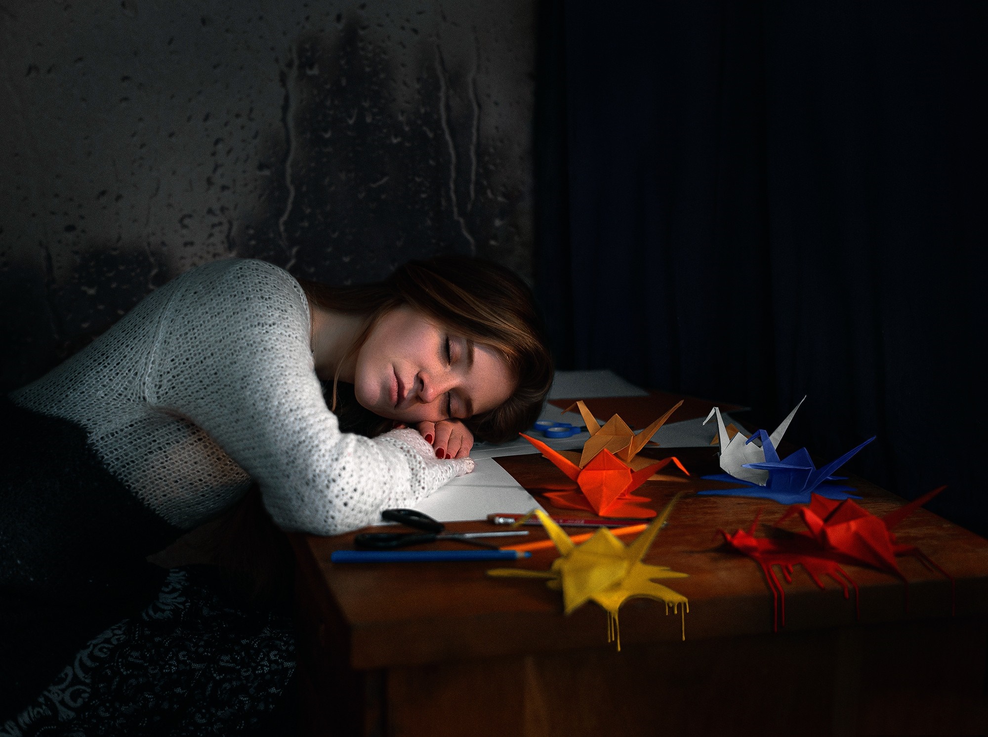 Woman sleeping at a desk with origami cranes HD Wallpaper