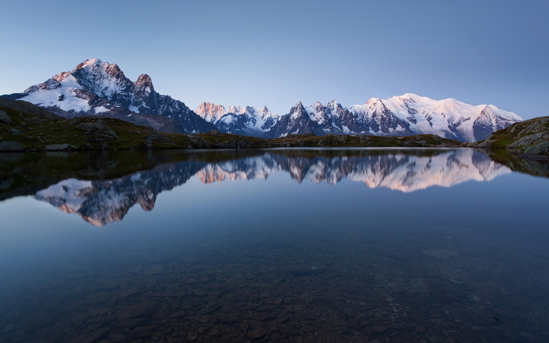 Snow-capped mountains reflected in a calm lake HD Wallpaper