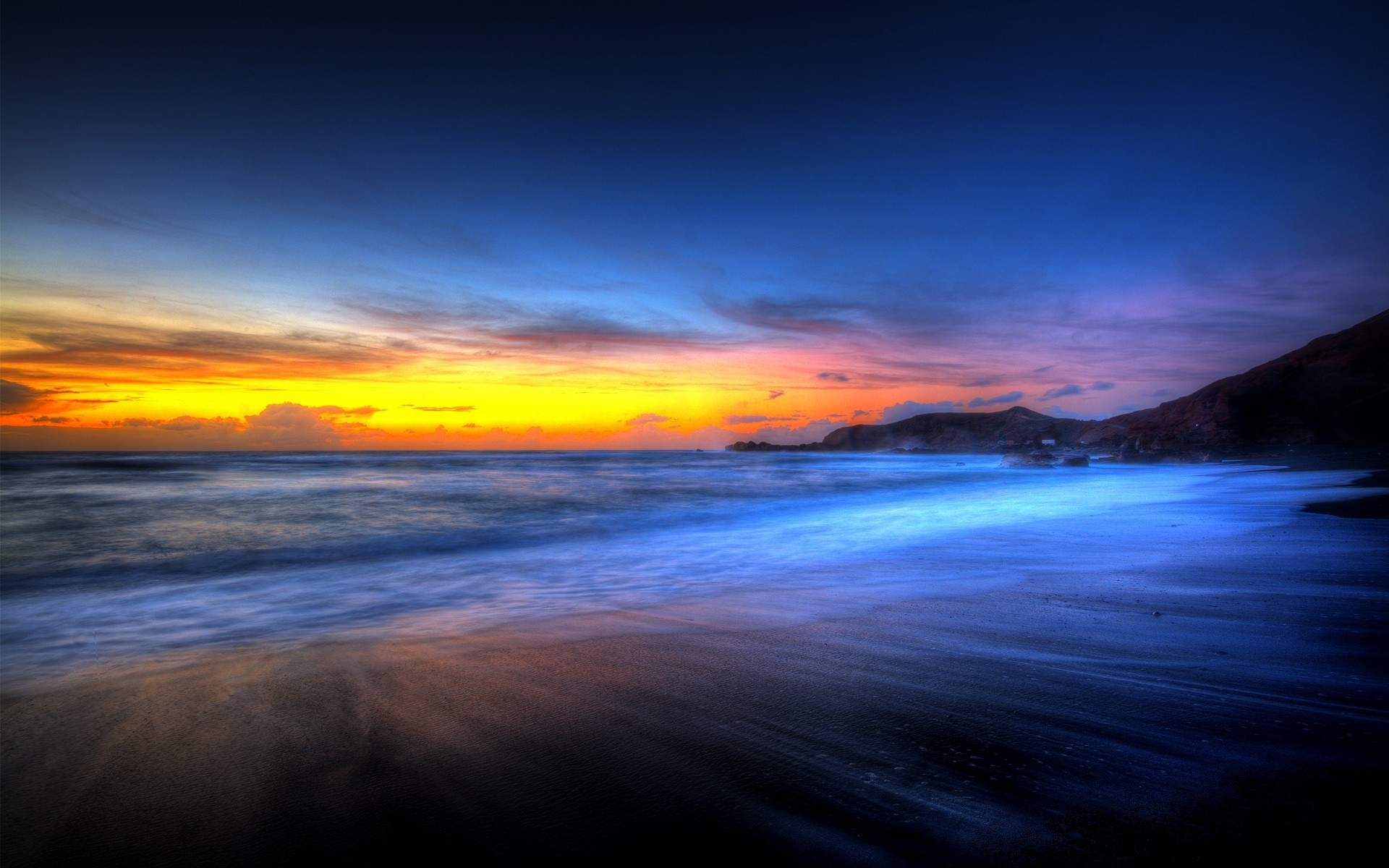 Sunset over a beach with waves and mountains HD Wallpaper