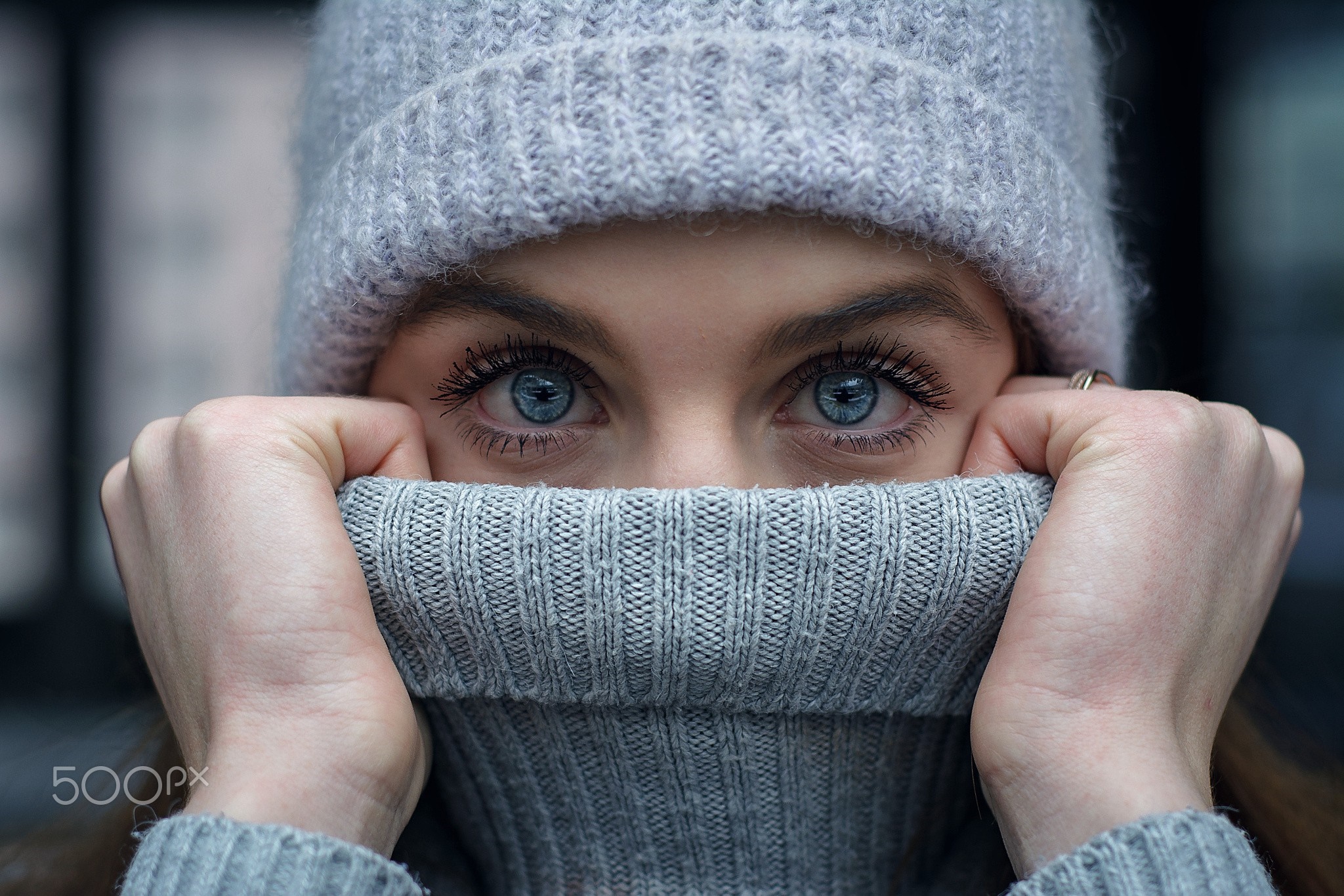 Close up of a woman's blue eyes wearing a grey beanie and turtleneck HD Wallpaper