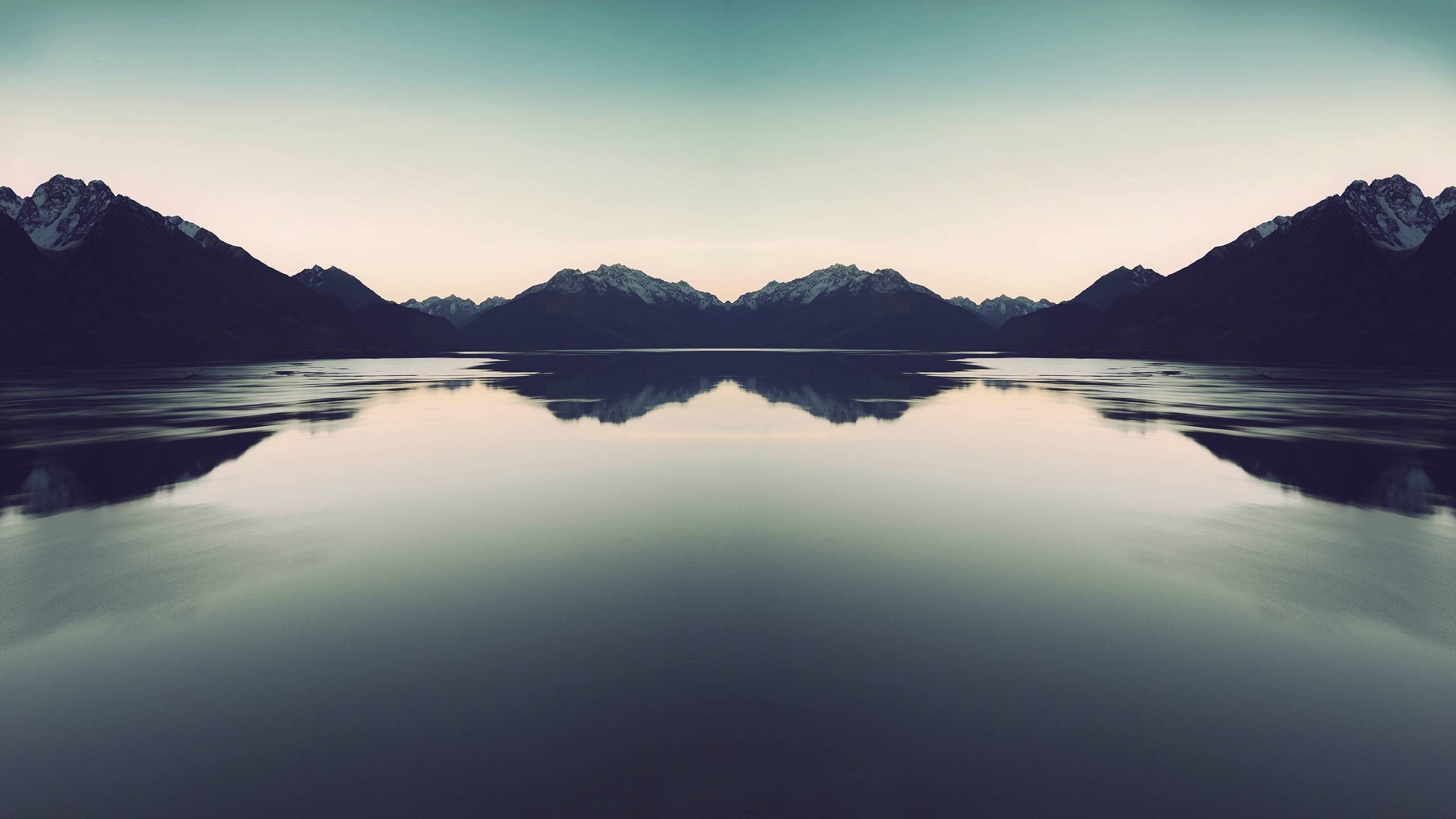Symmetrical mountain range reflected in a calm lake at dawn HD Wallpaper