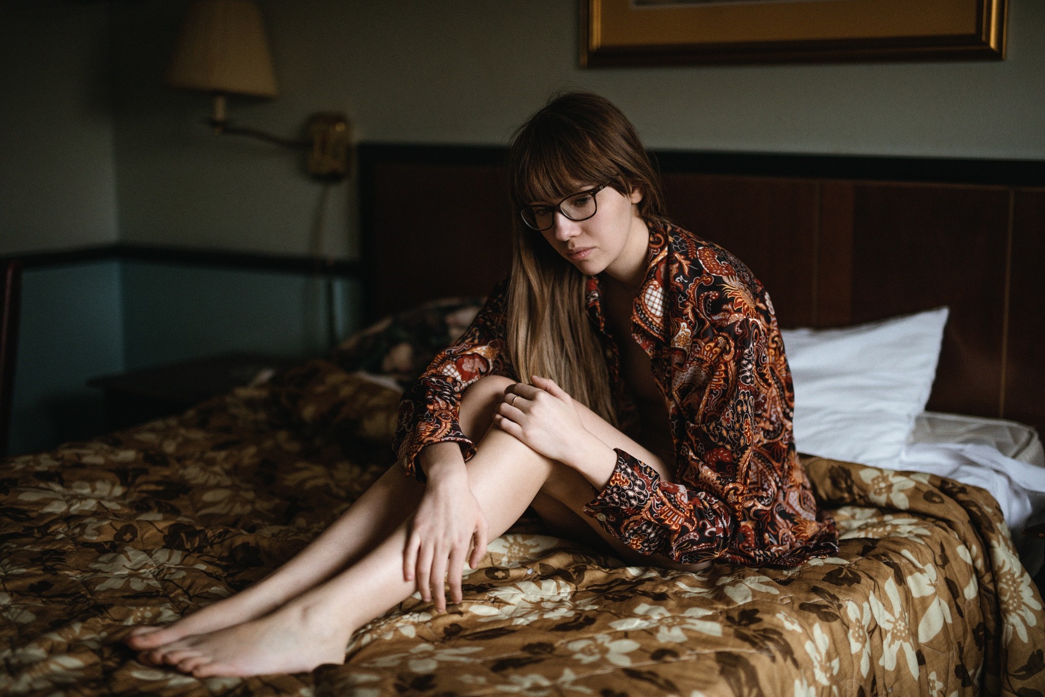 Woman with glasses sitting on a bed HD Wallpaper