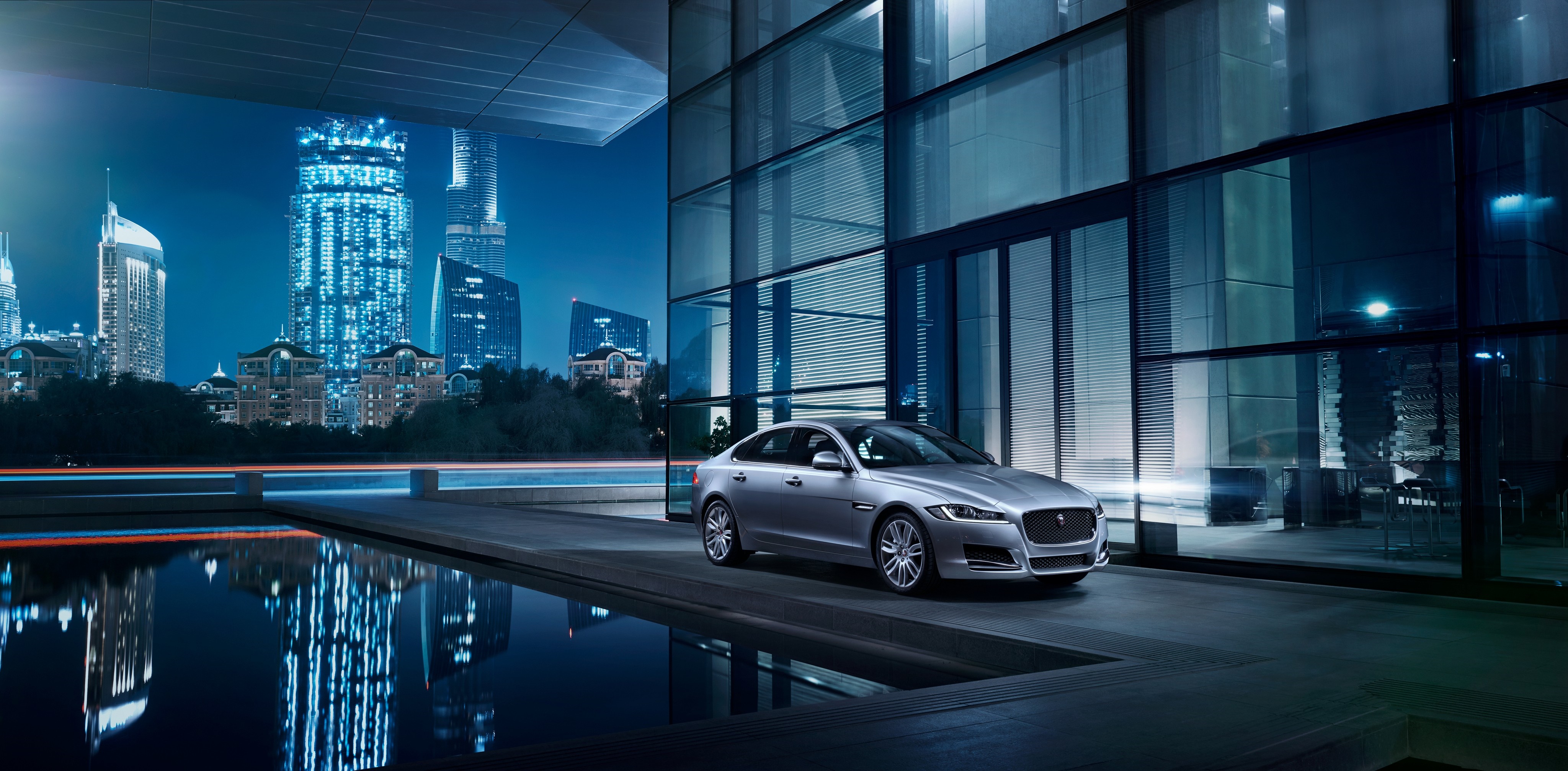 Jaguar car parked by modern building at night HD Wallpaper