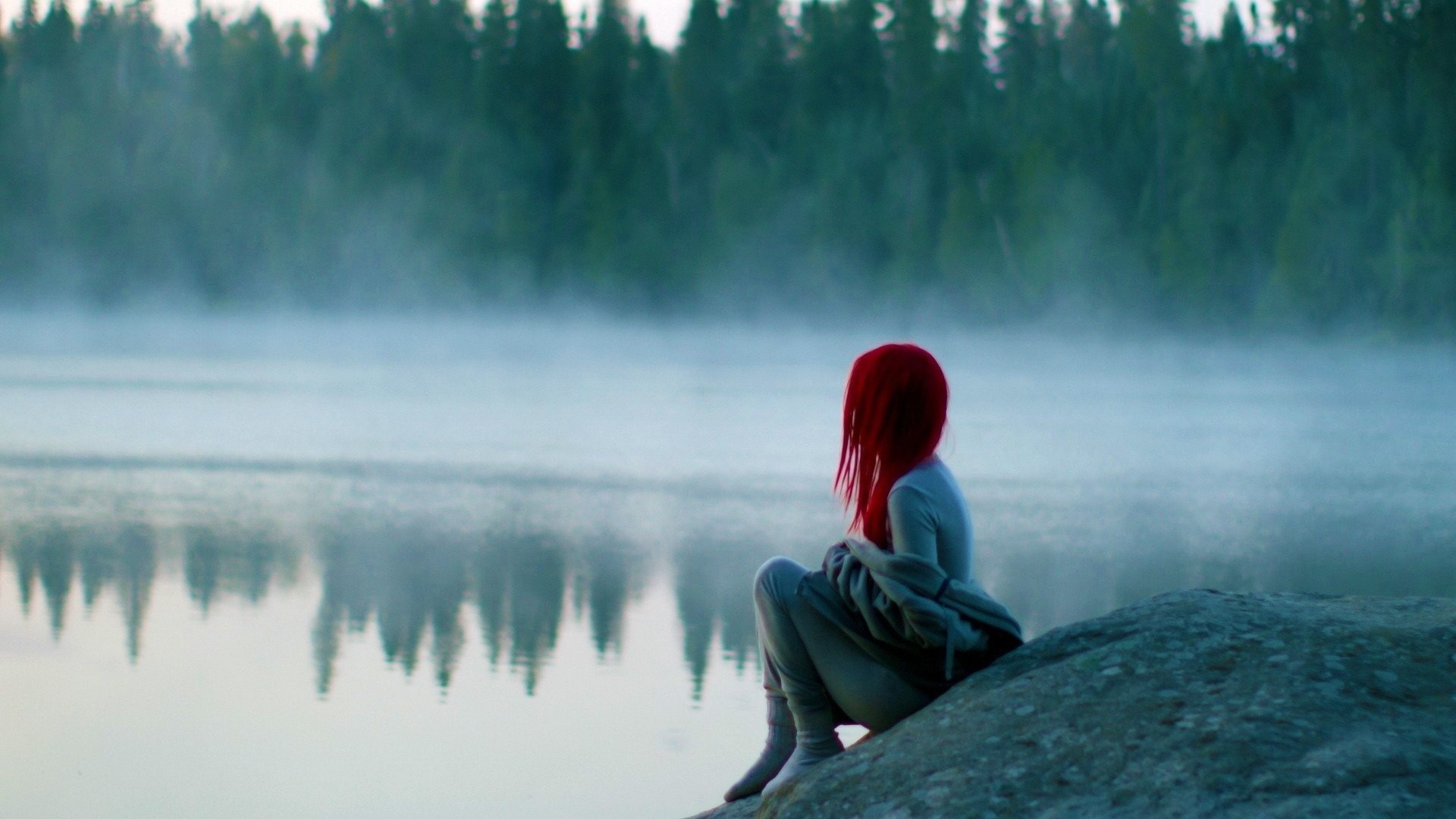 Redhead woman sitting by a misty lake at sunrise HD Wallpaper