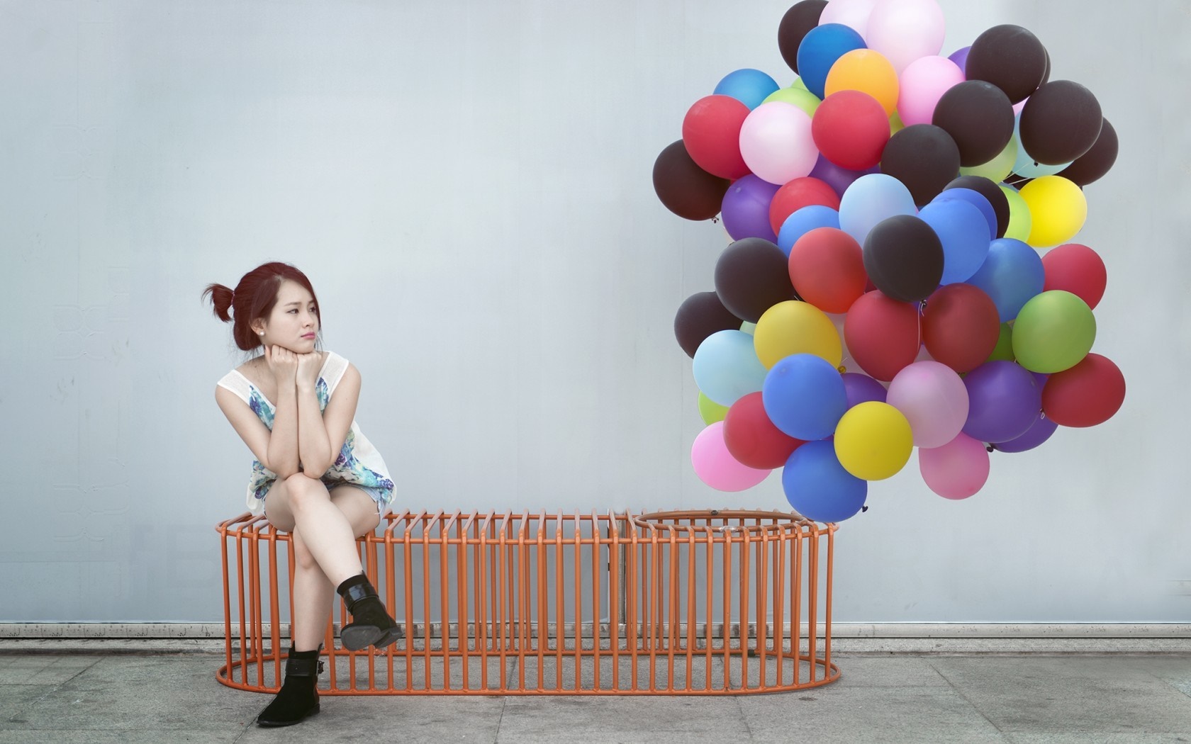 Woman sitting on orange bench with colorful balloons HD Wallpaper