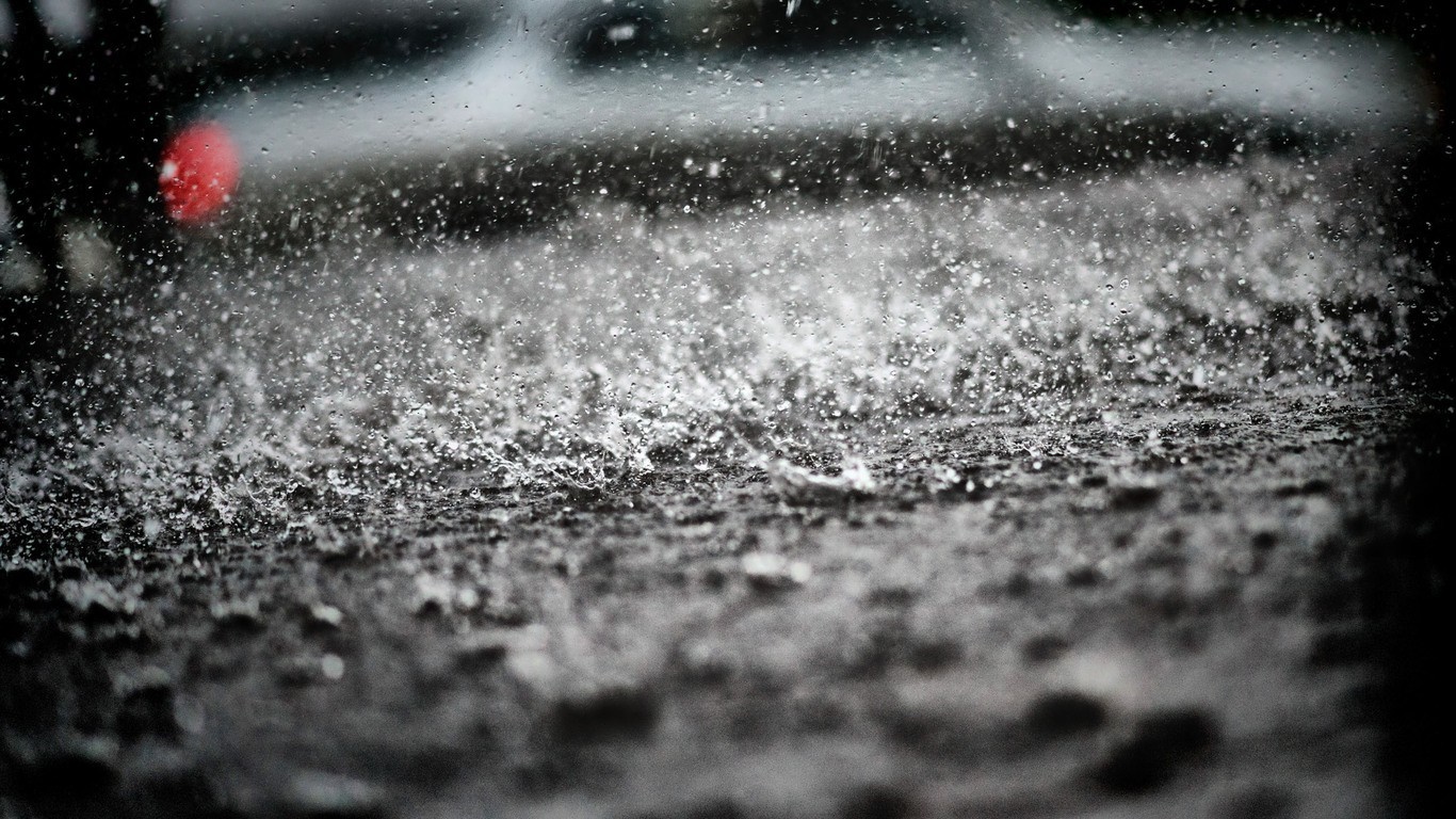 Raindrops splashing on a dark surface HD Wallpaper